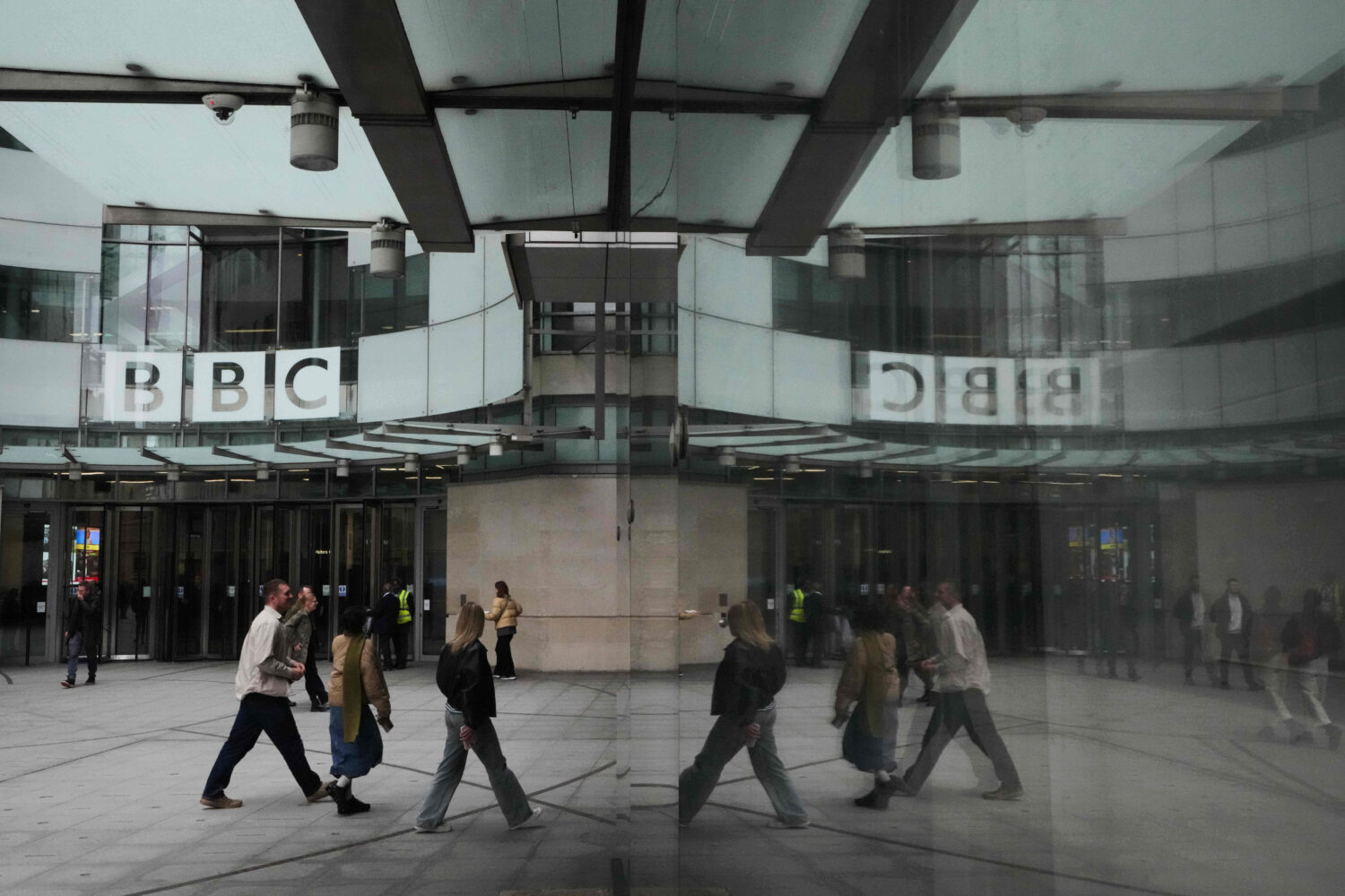 Pedestrians are reflected as they walk outside BBC Broadcasting House in London, Tuesday, Nov. 11, ...