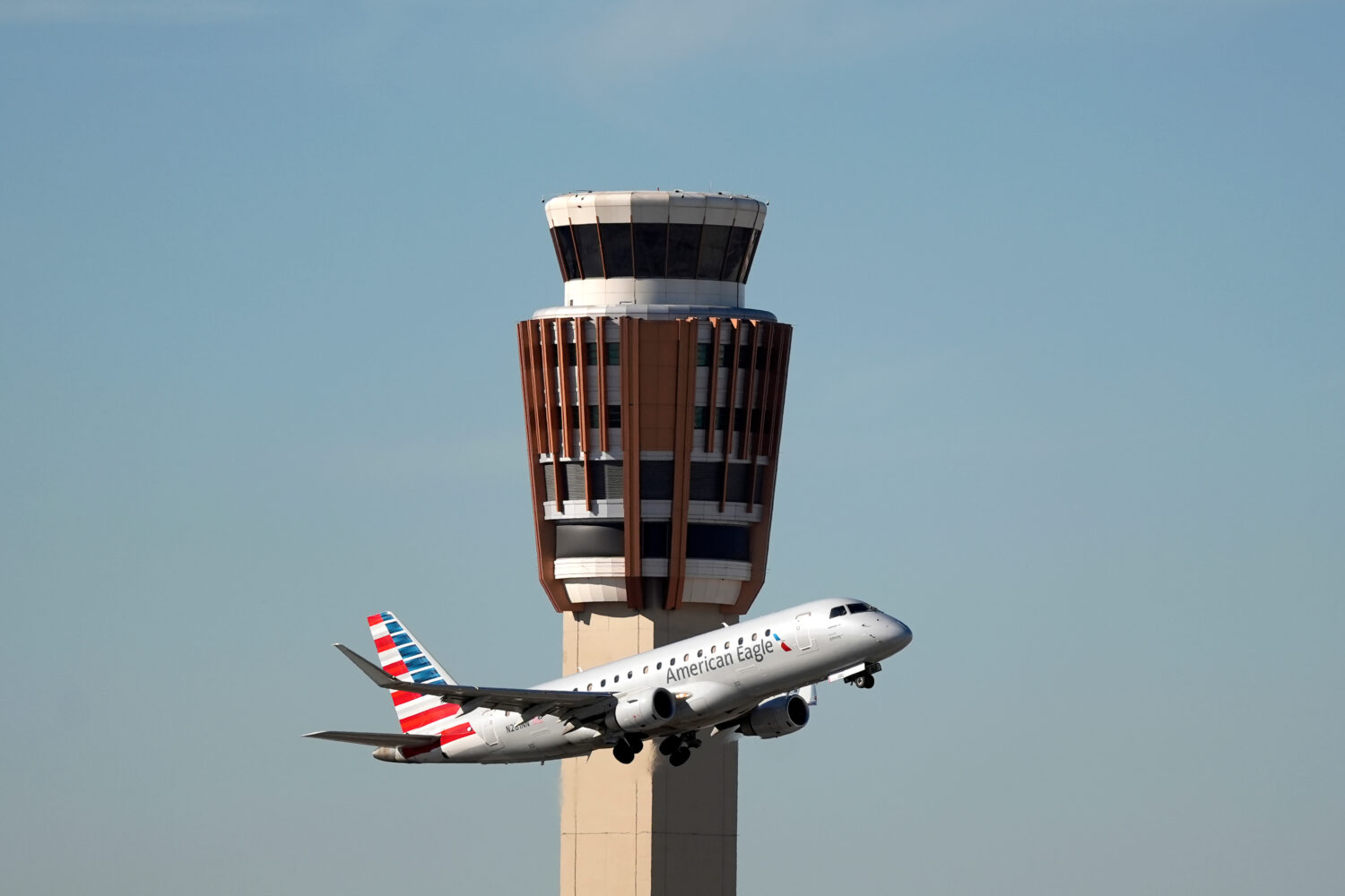 An American Airlines American Eagle jet flies past the air traffic control tower at Phoenix Sky Har...