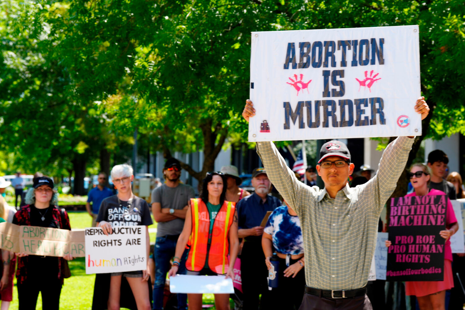 FILE - A man supporting restrictions on abortion holds a sign as abortion-rights supporters hold si...