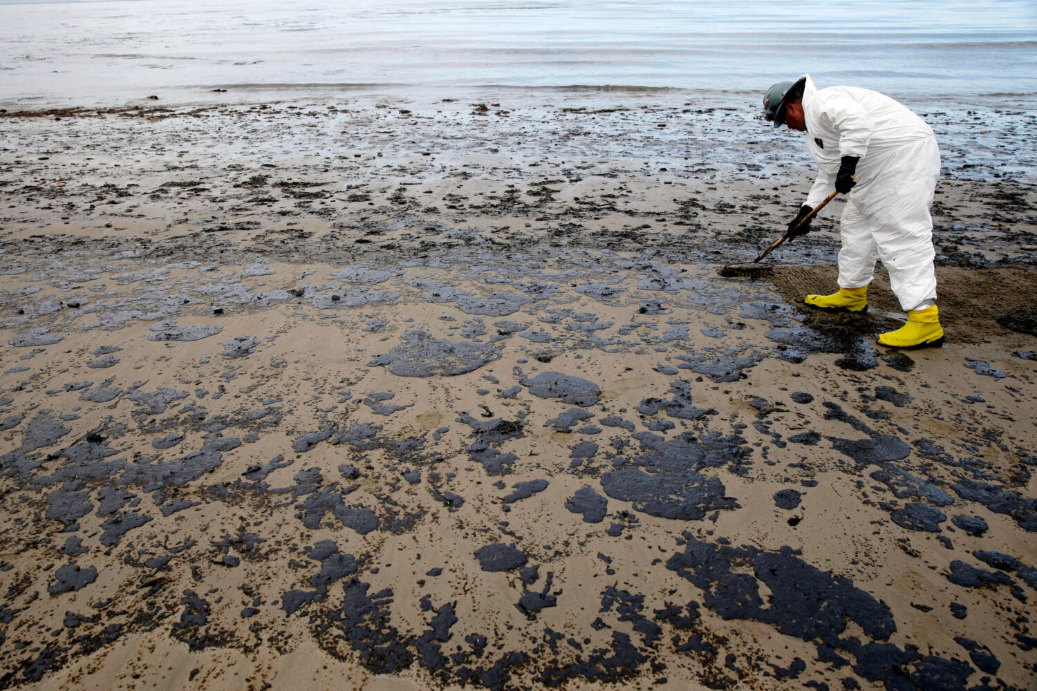 FILE - A worker removes oil from the sand at Refugio State Beach, north of Goleta, Calif., May 21, ...