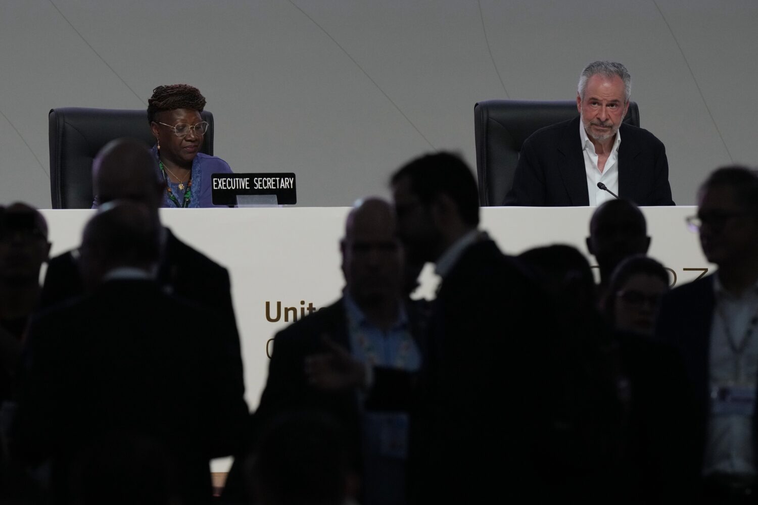 People come and go from a plenary session as André Corrêa do Lago, COP30 president, sits at back ...