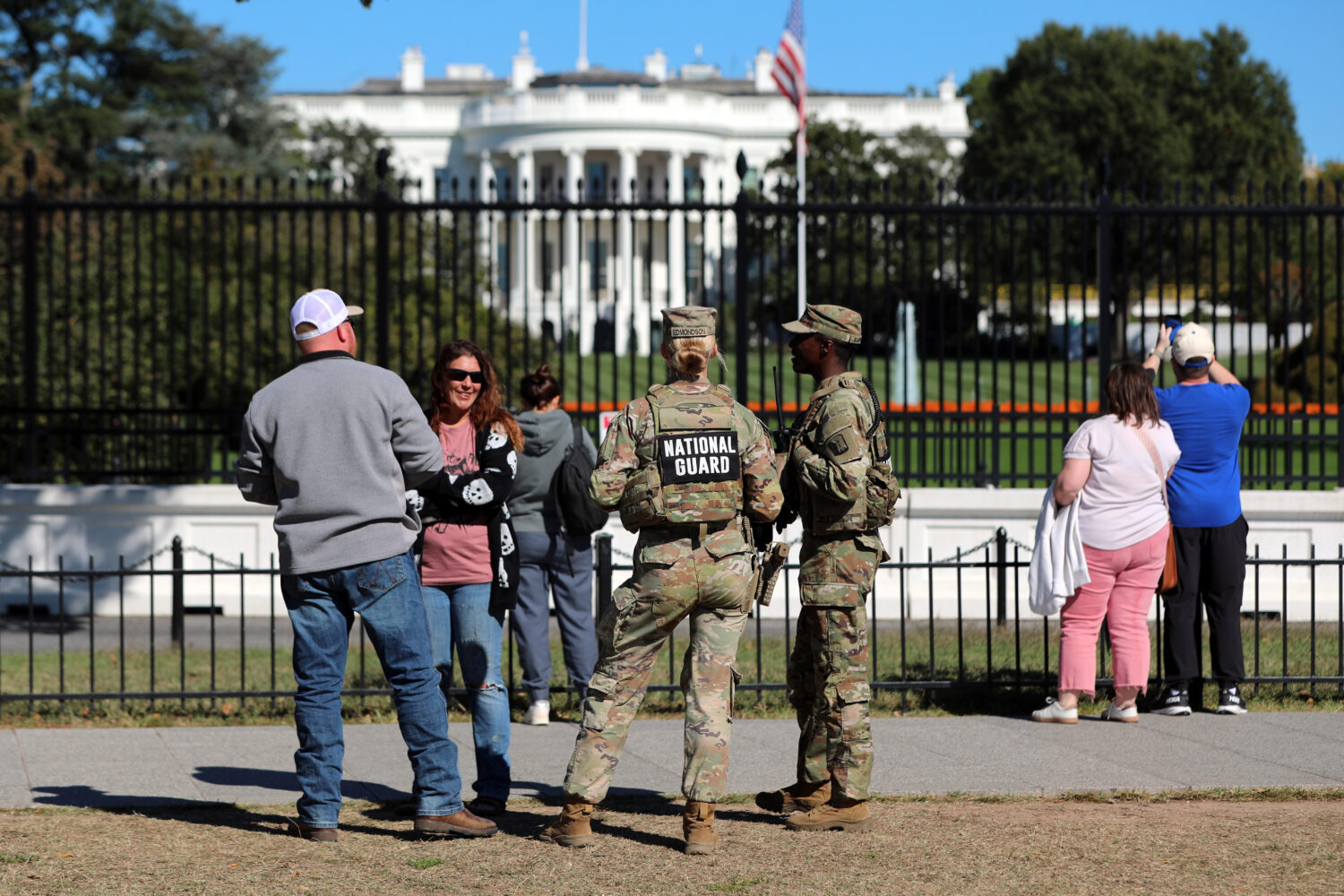 FILE - People talk with National Guard soldiers on the Ellipse, with the White House in the backgro...
