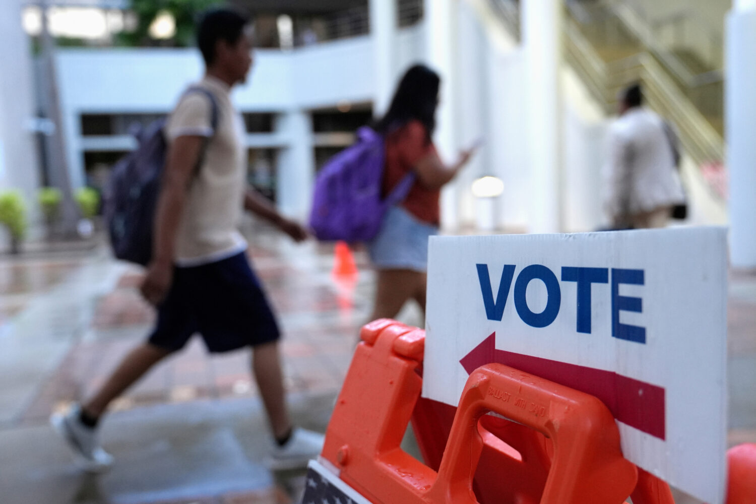 FILE - People walk past a "vote" sign on the first day of early voting in the general election in M...