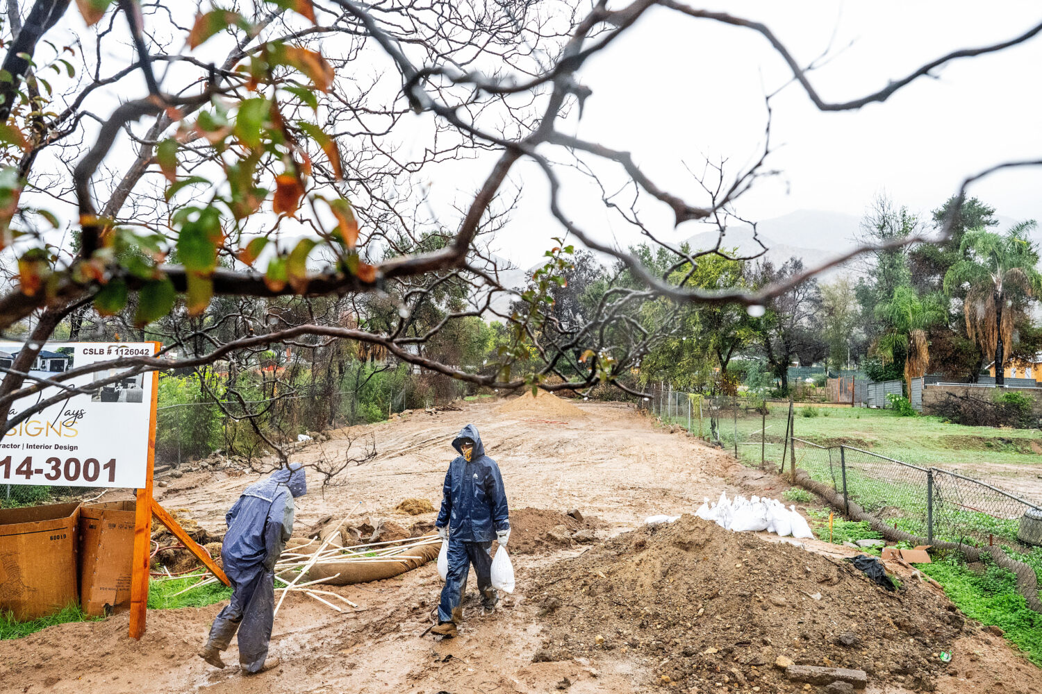 James Jones carries sandbags while trying to prevent water from running off a property scorched in ...