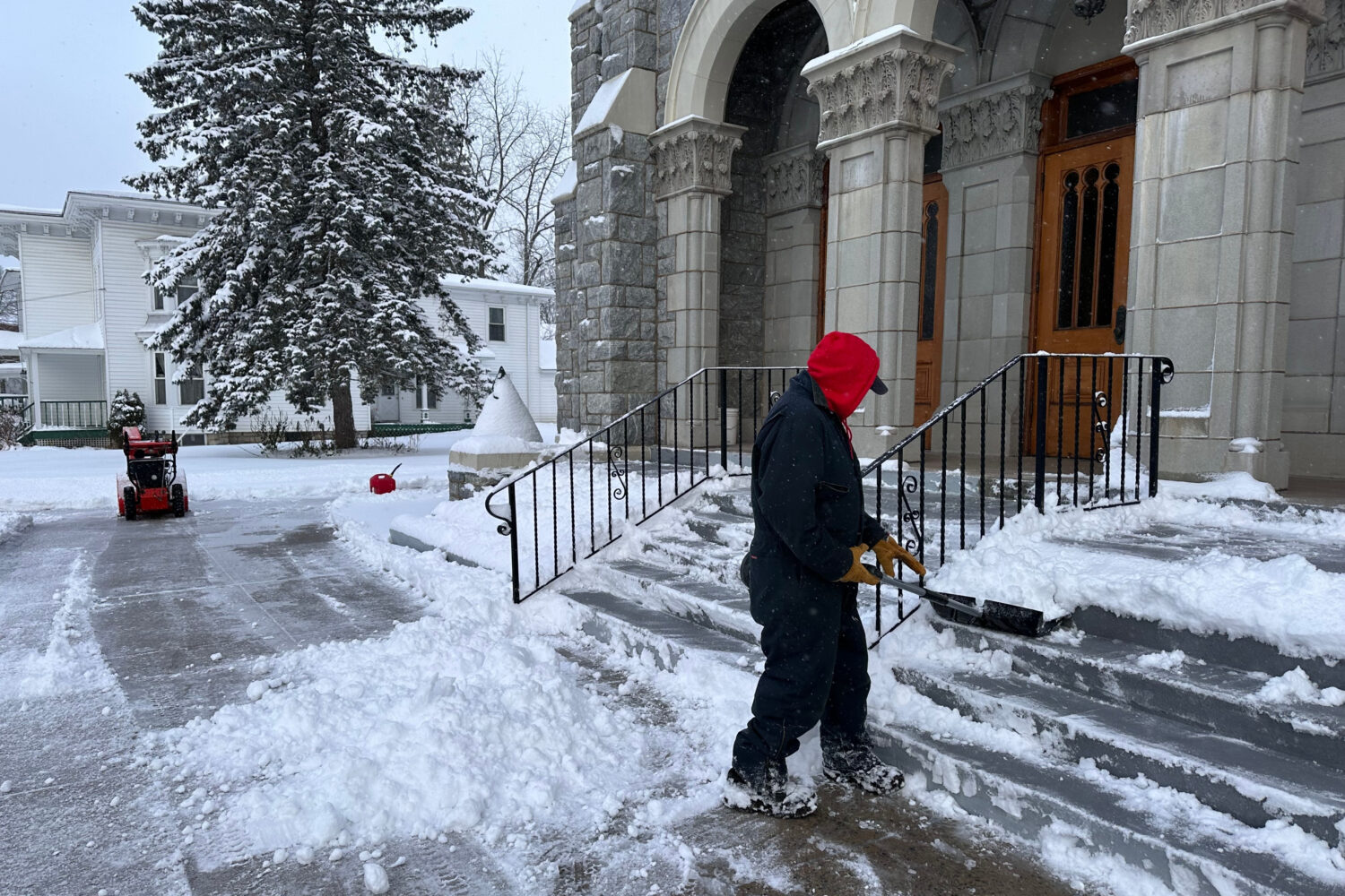 A man shovels snow outside a church in Lowville, N.Y., on Friday, Nov. 28, 2025. (AP Photo/Cara Ann...