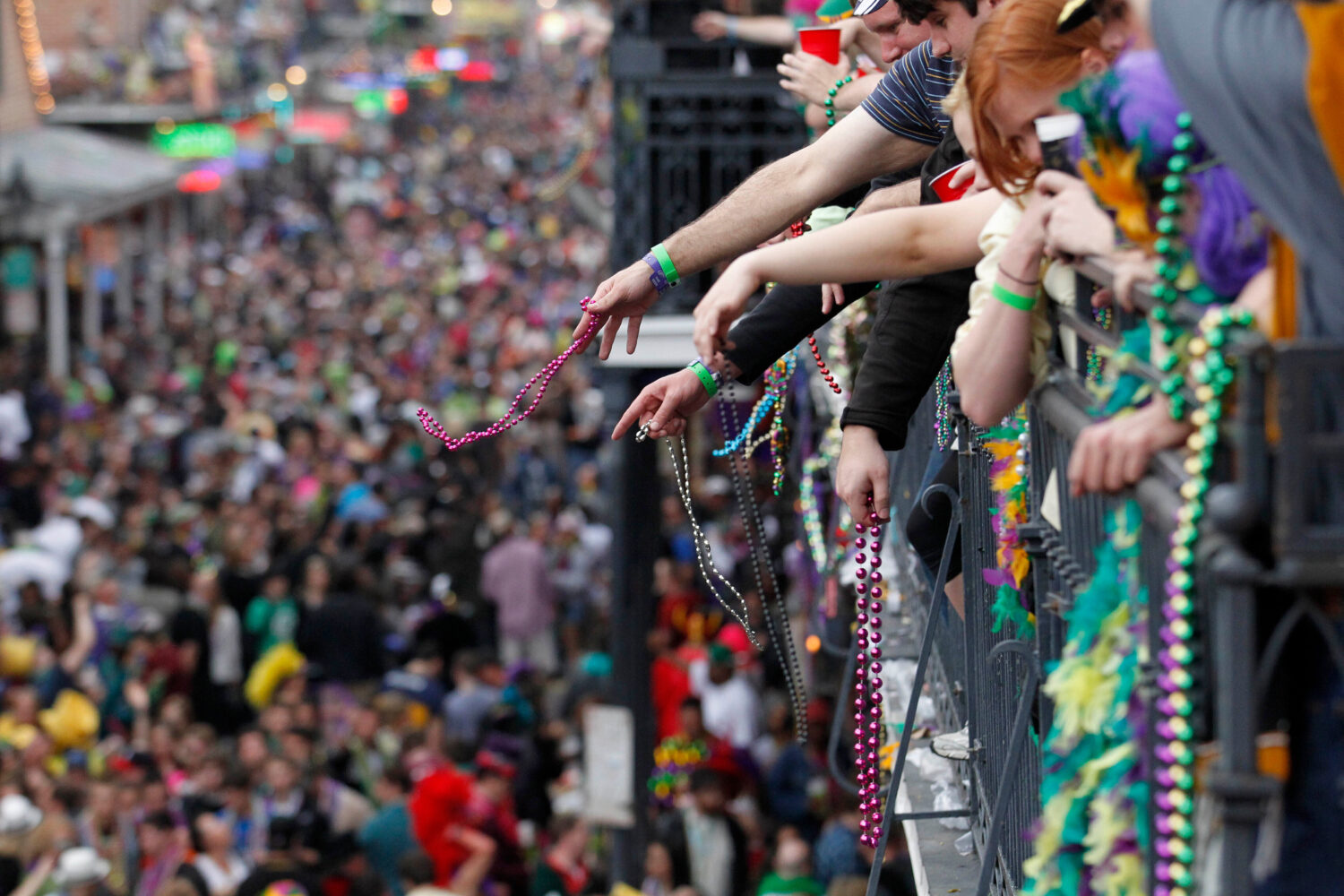 FILE - Revelers throw beads from the balcony of the Royal Sonesta Hotel onto crowds on Bourbon Stre...