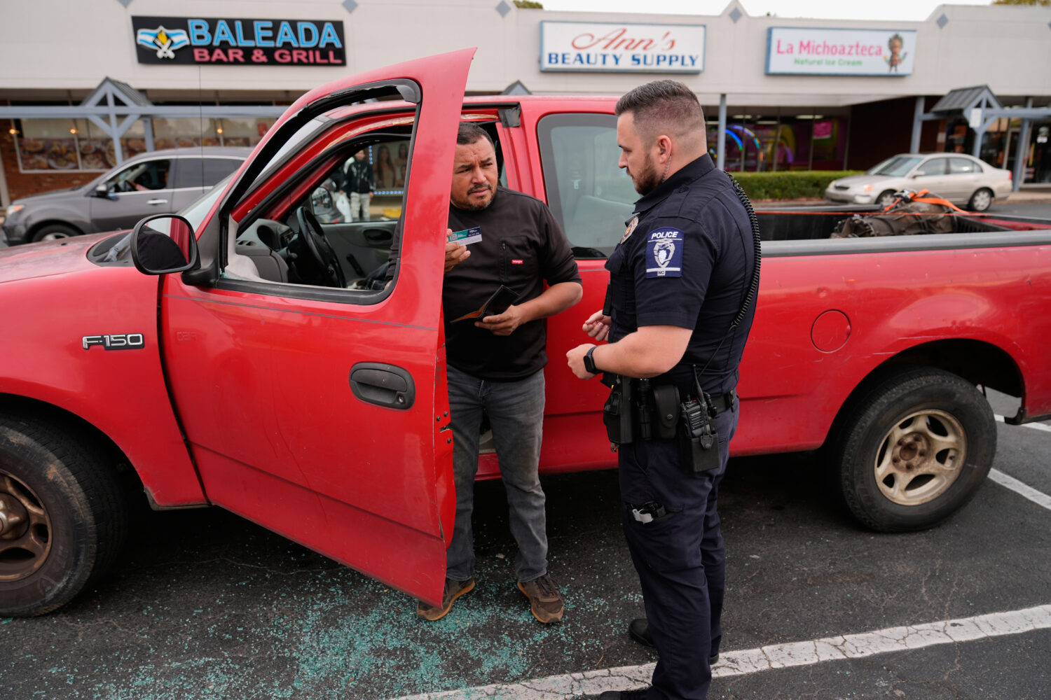 Willy Aceituno, left, makes a police report with Charlotte-Mecklenburg Police Department officer N....