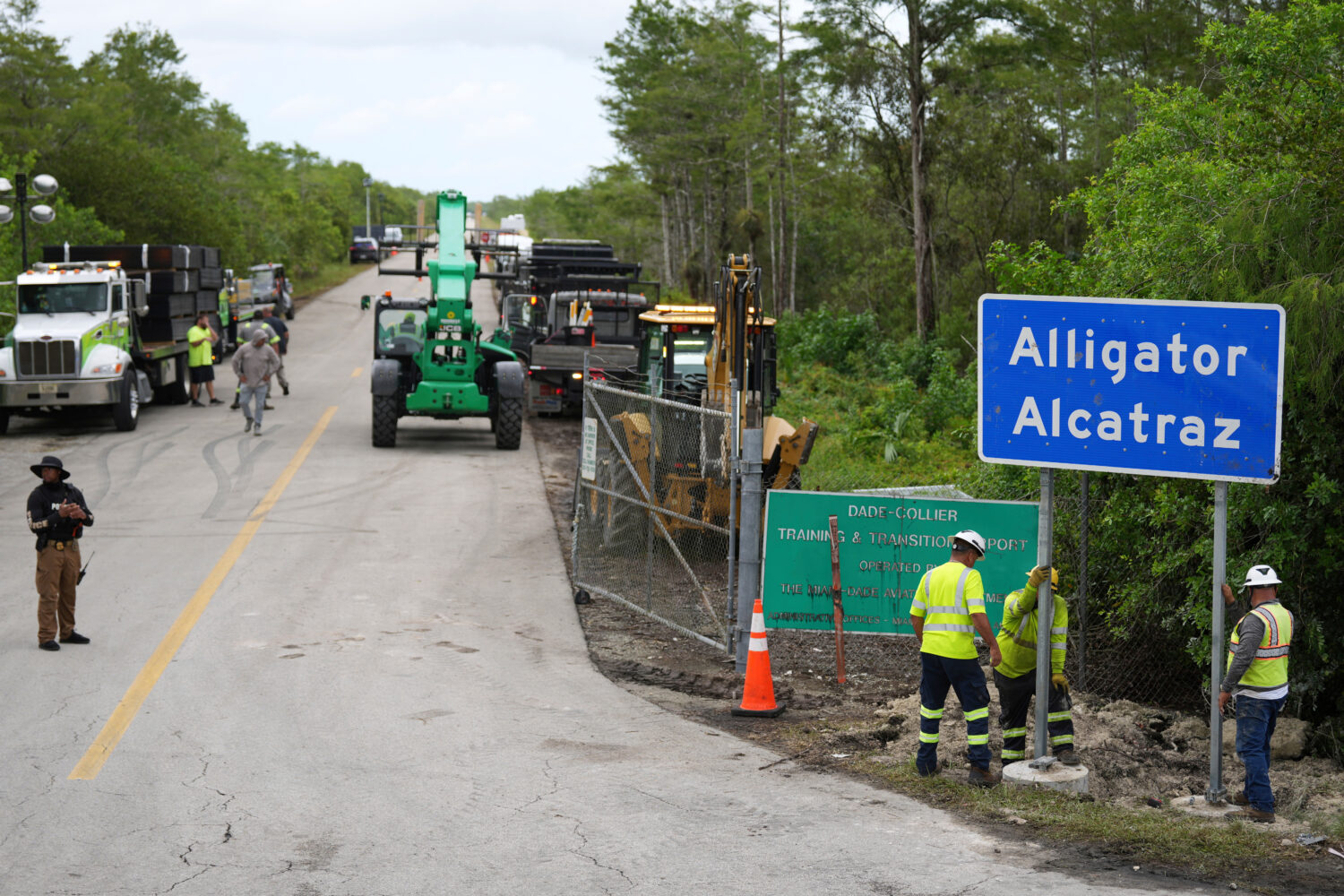 FILE - Workers install a sign reading "Alligator Alcatraz" at the entrance to the migrant detention...