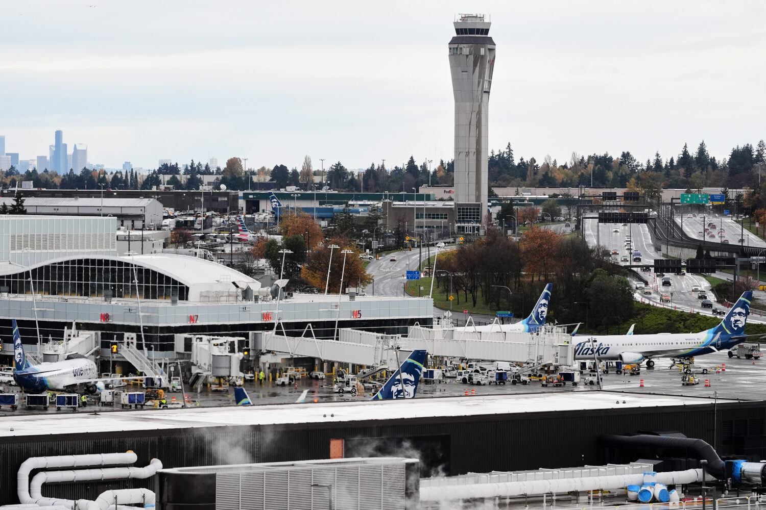 The air traffic control tower is seen at the distance as Alaska Airlines planes sit at the gates at...