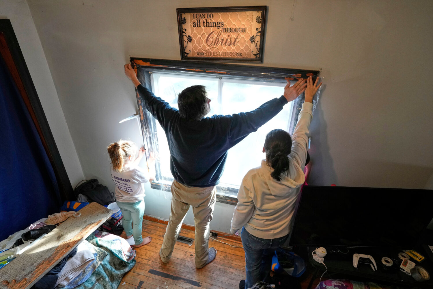 Gerard Berry, along with his wife, Stephanie, and daughter, Brooklynn, cover a bedroom window with ...