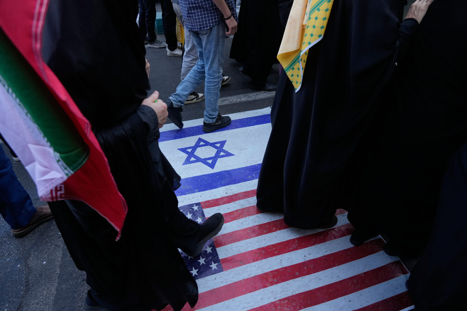 Demonstrators walk on a representation of the U.S. and Israeli flags during an annual rally in fron...