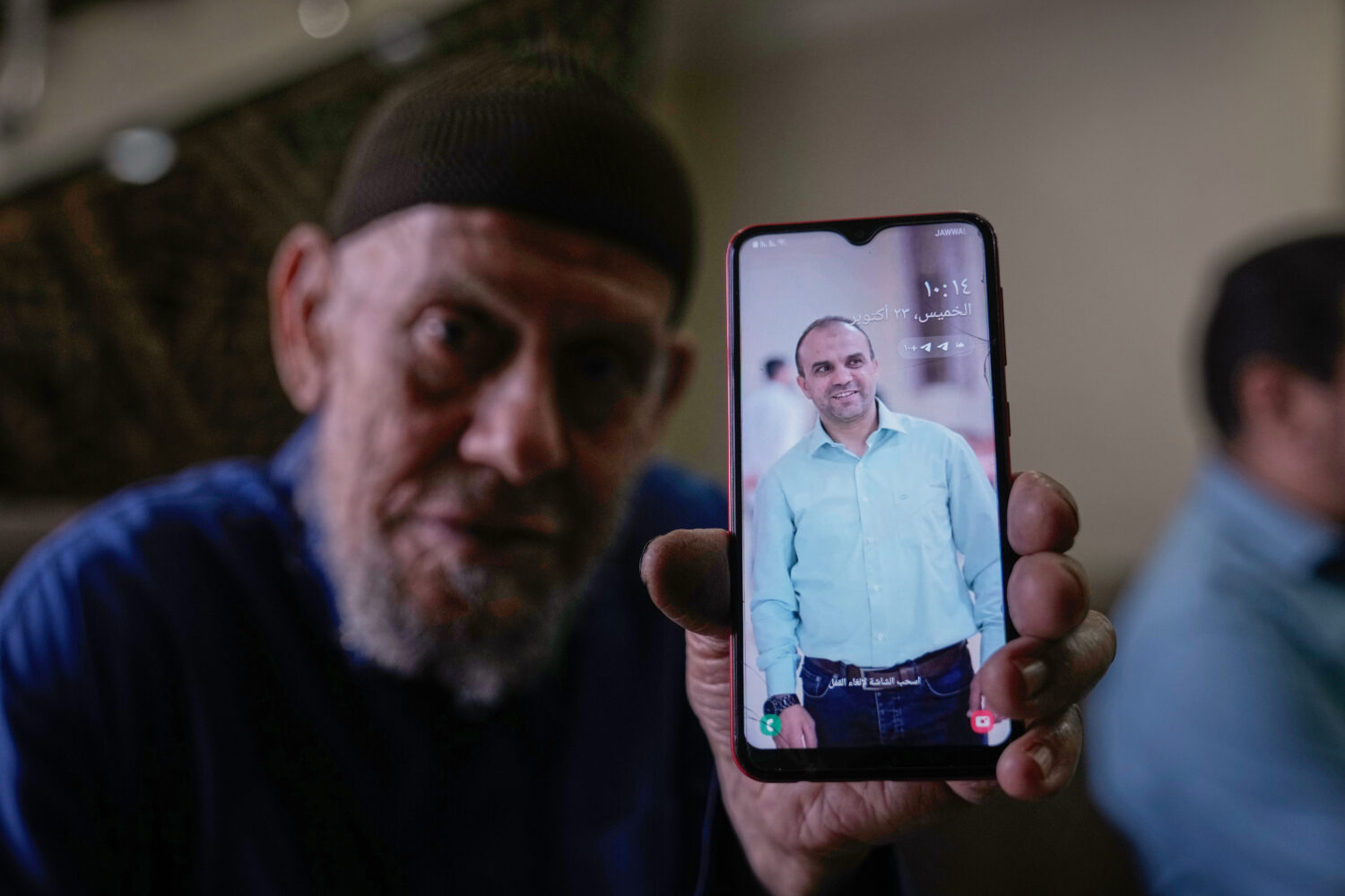 Waleed Husein Ali, shows a picture on a phone of his son, Mohammad, 45, who died in Israeli custody...