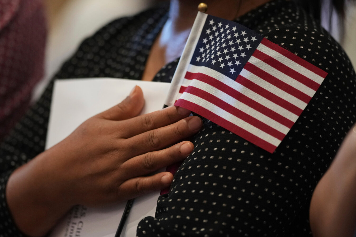 FILE - A woman clutches a U.S. flag as she and applicants from other countries prepare to take the ...