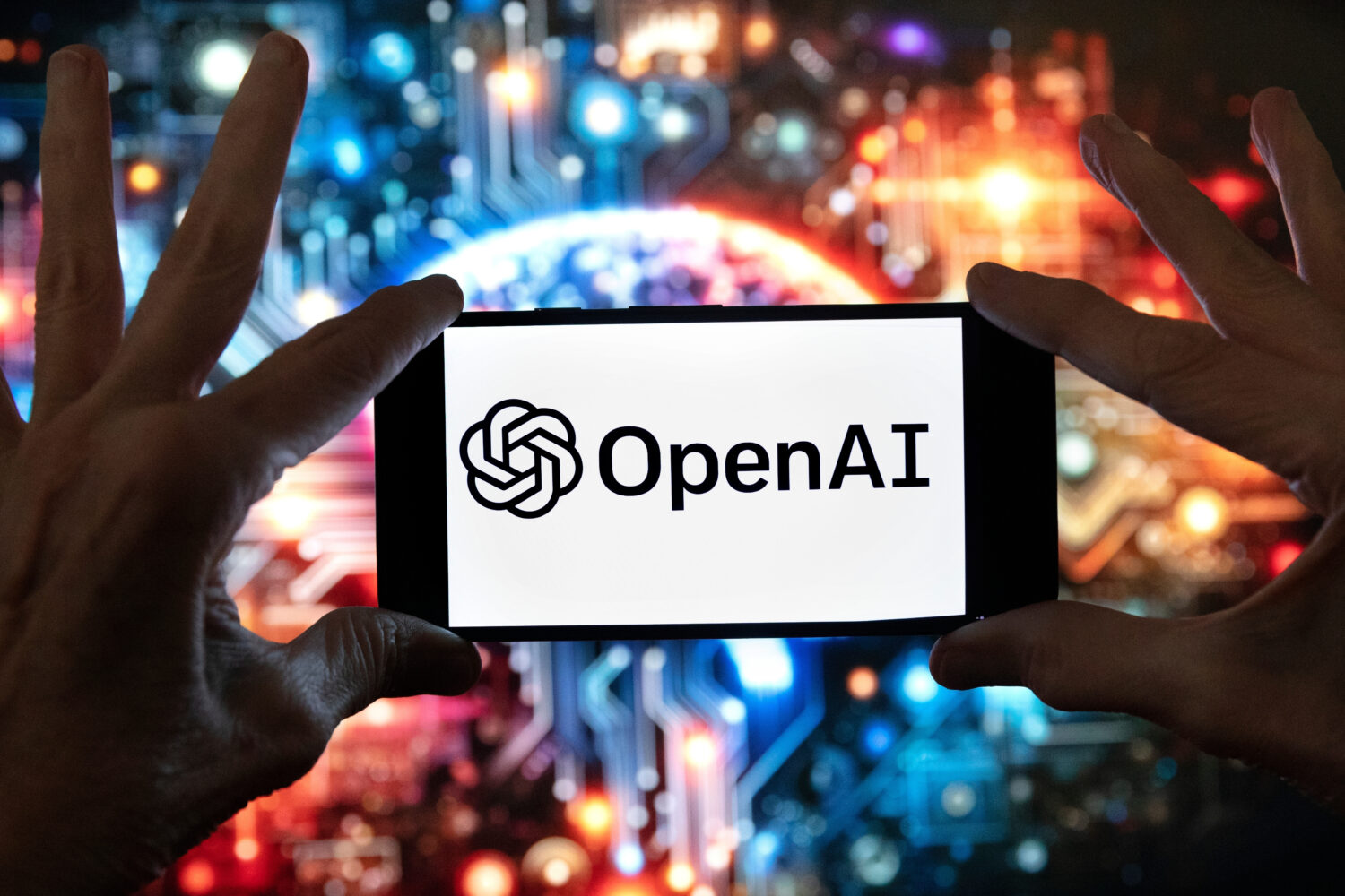 FILE - The OpenAI logo is seen displayed on a cell phone in front of an image on a computer screen ...