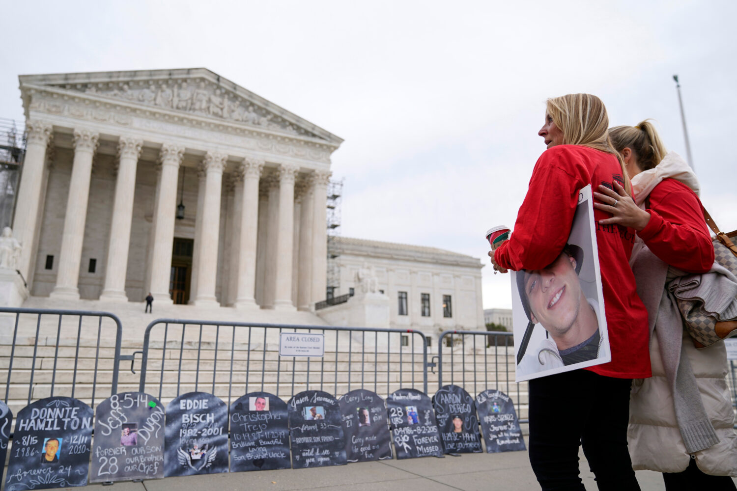 FILE - Jen Trejo holds a photo of her son Christopher as she is comforted outside the Supreme Court...