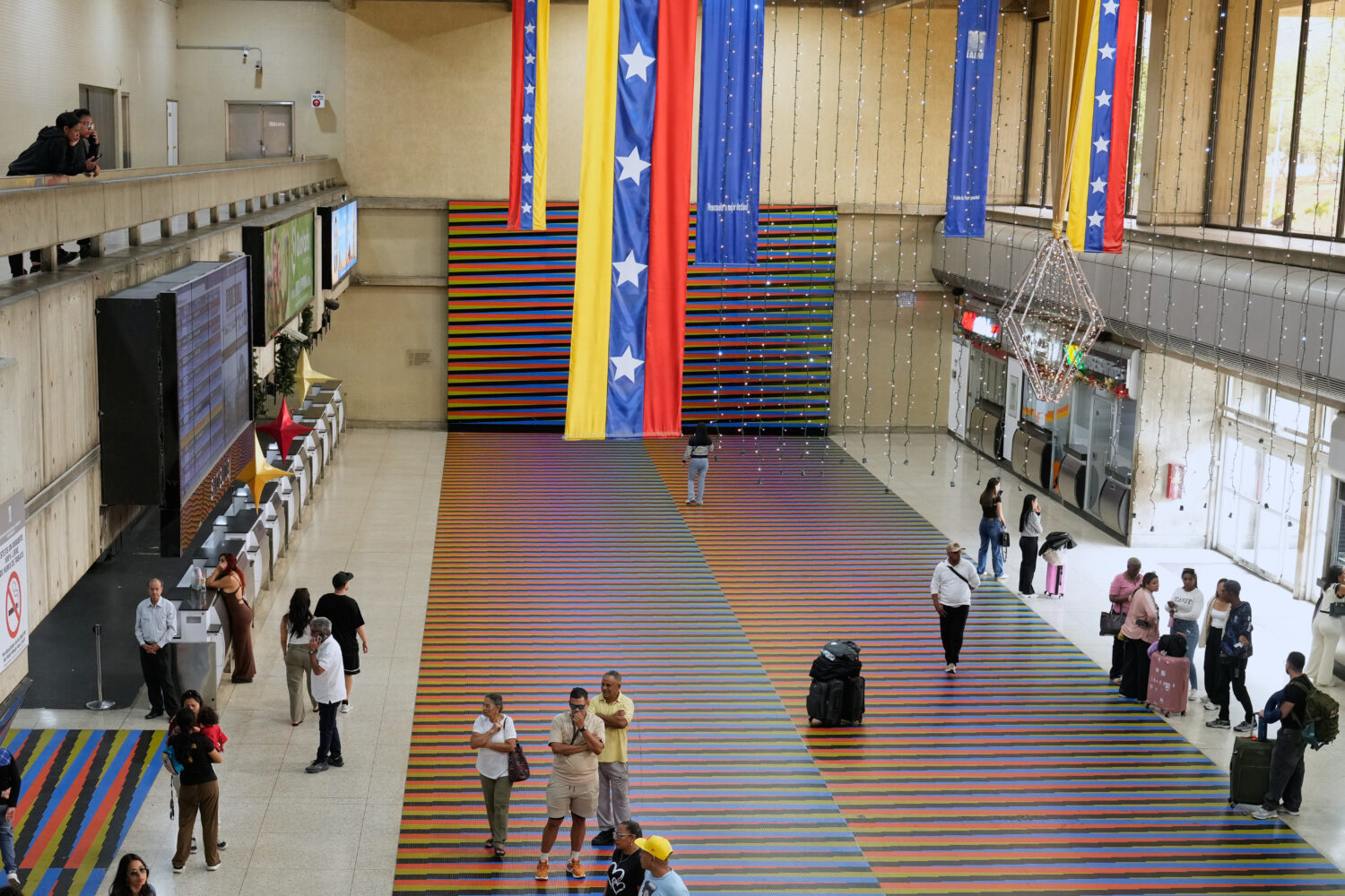 Travelers wait in the main hall of the Simon Bolivar Maiquetia International Airport in Maiquetia, ...