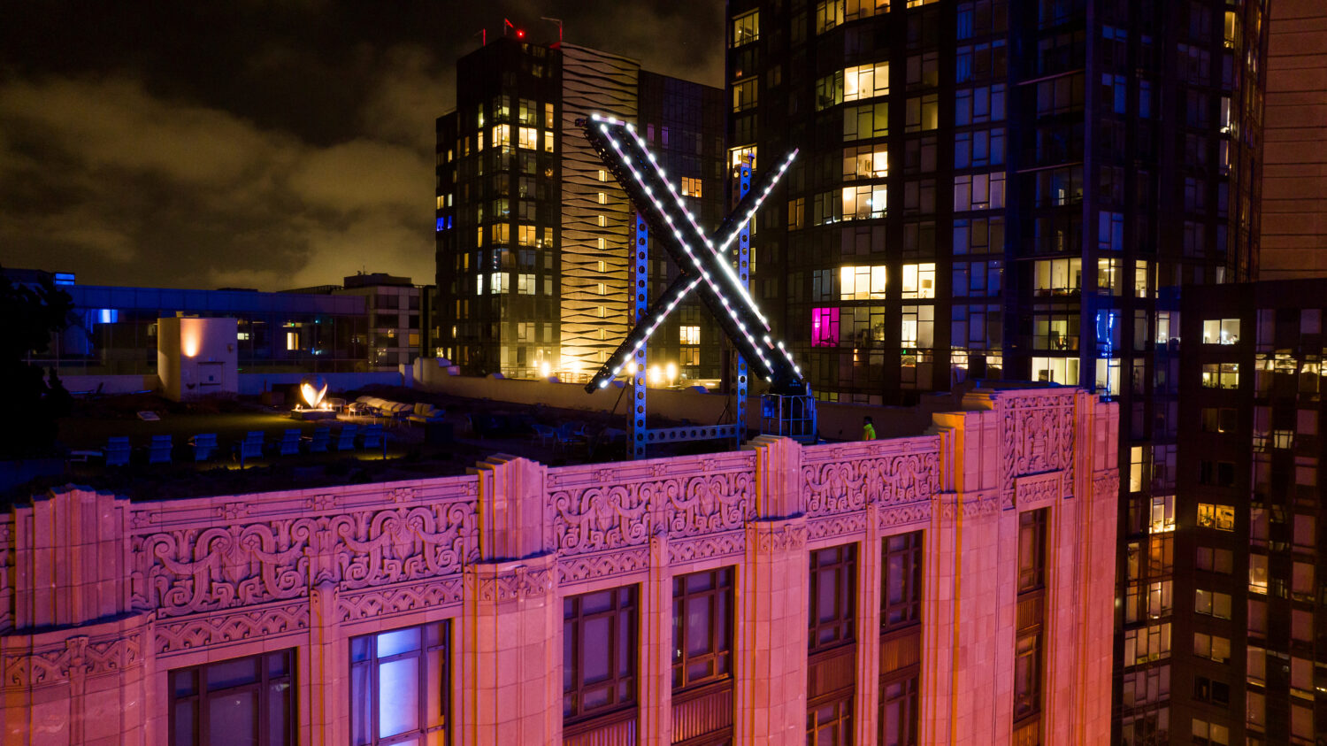 FILE - Workers install lighting on an "X" sign atop the company headquarters in downtown San Franci...