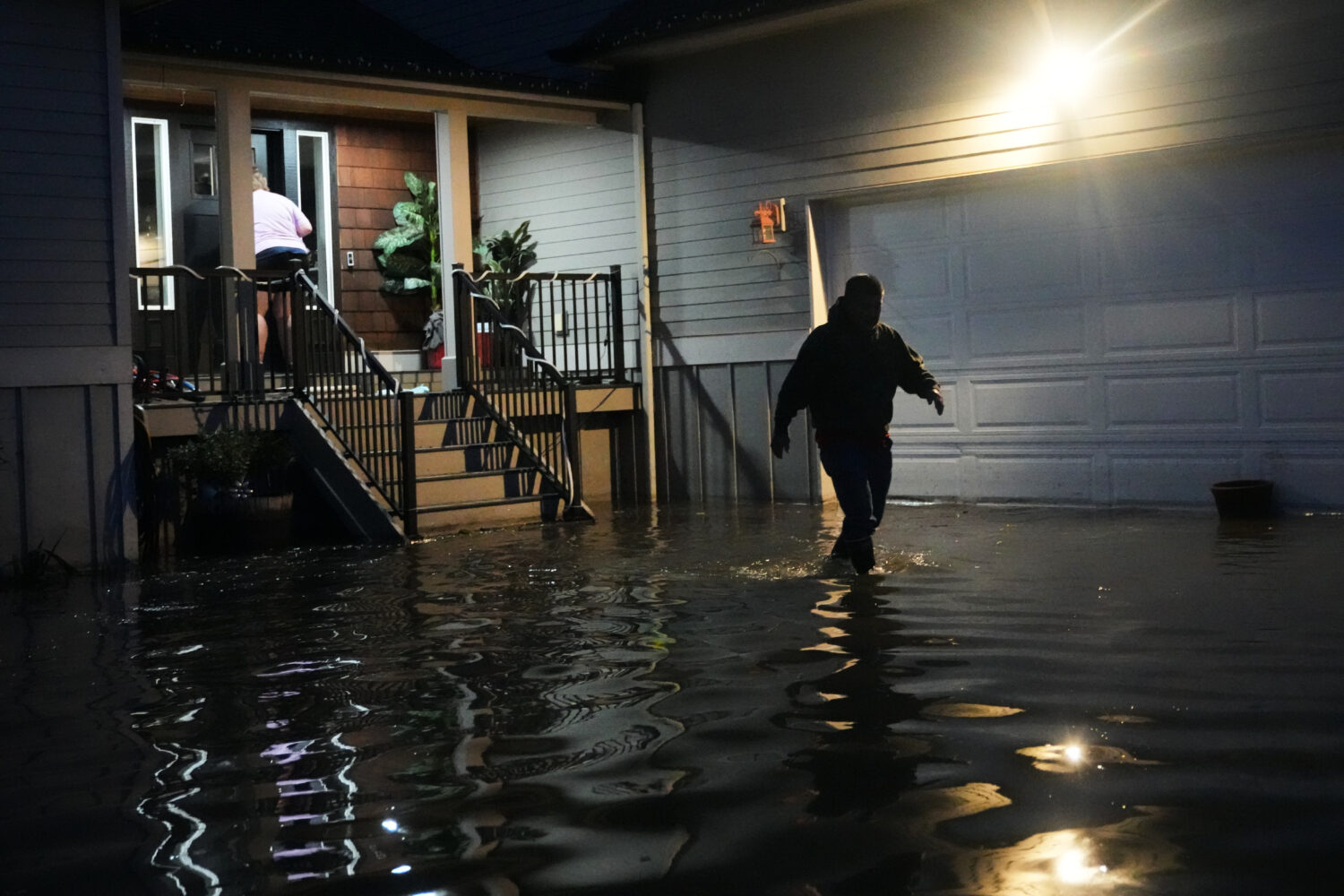 Haji Higa, right, and Lydia Heglin, left, walk through floodwaters at their front door after heavy ...