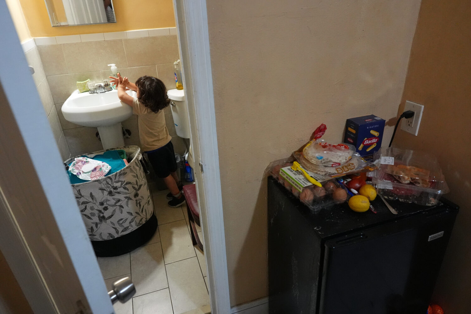 Jakelin Pasedo's three-year-old son washes his hands in the Miami-area motel room where Pasedo and ...