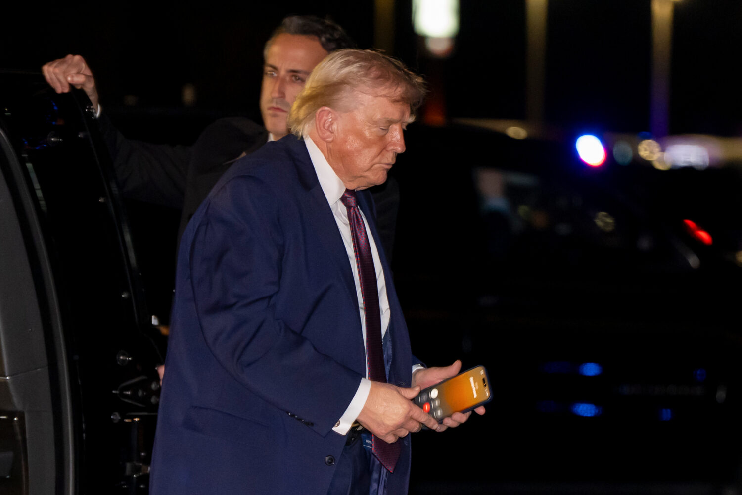 President Donald Trump holds a cell phone with a call to Nvidia CEO Jensen Huang as he departs on A...