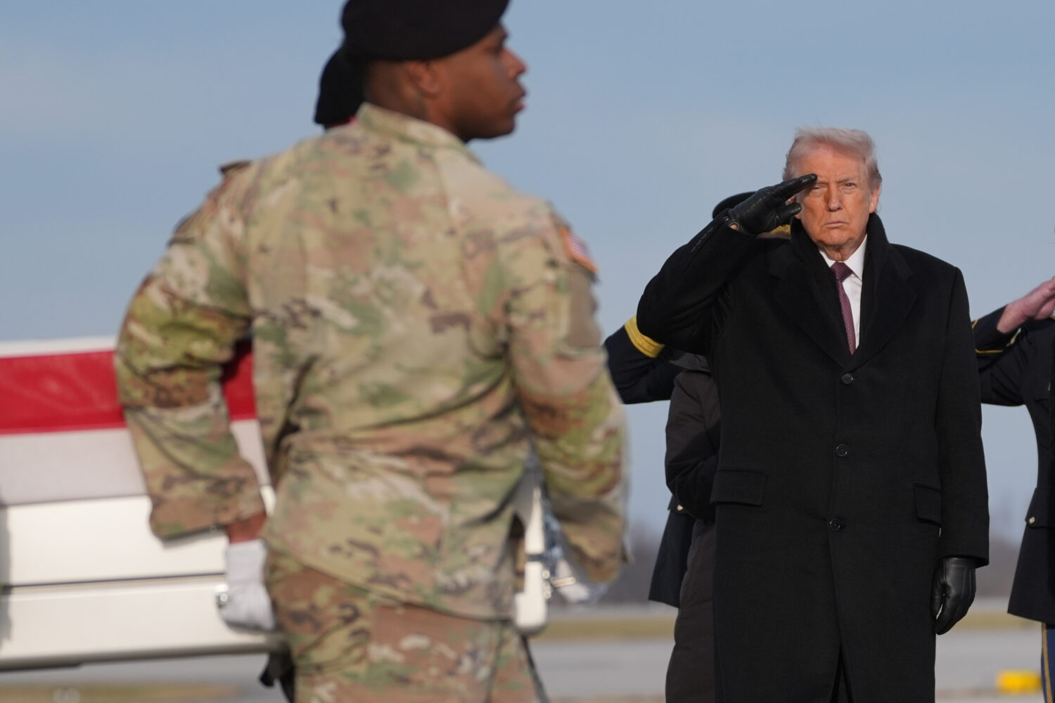 President Donald Trump salutes as a Army carry team moves the flag-draped transfer case with the re...