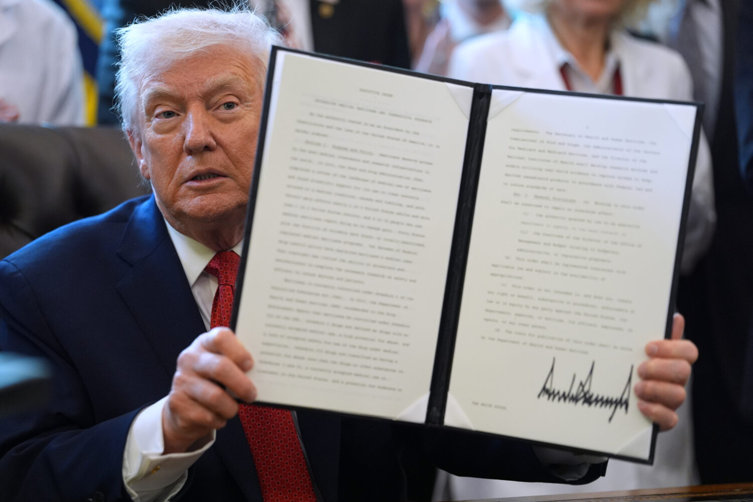 President Donald Trump displays an executive order reclassifying marijuana as a less dangerous drug...