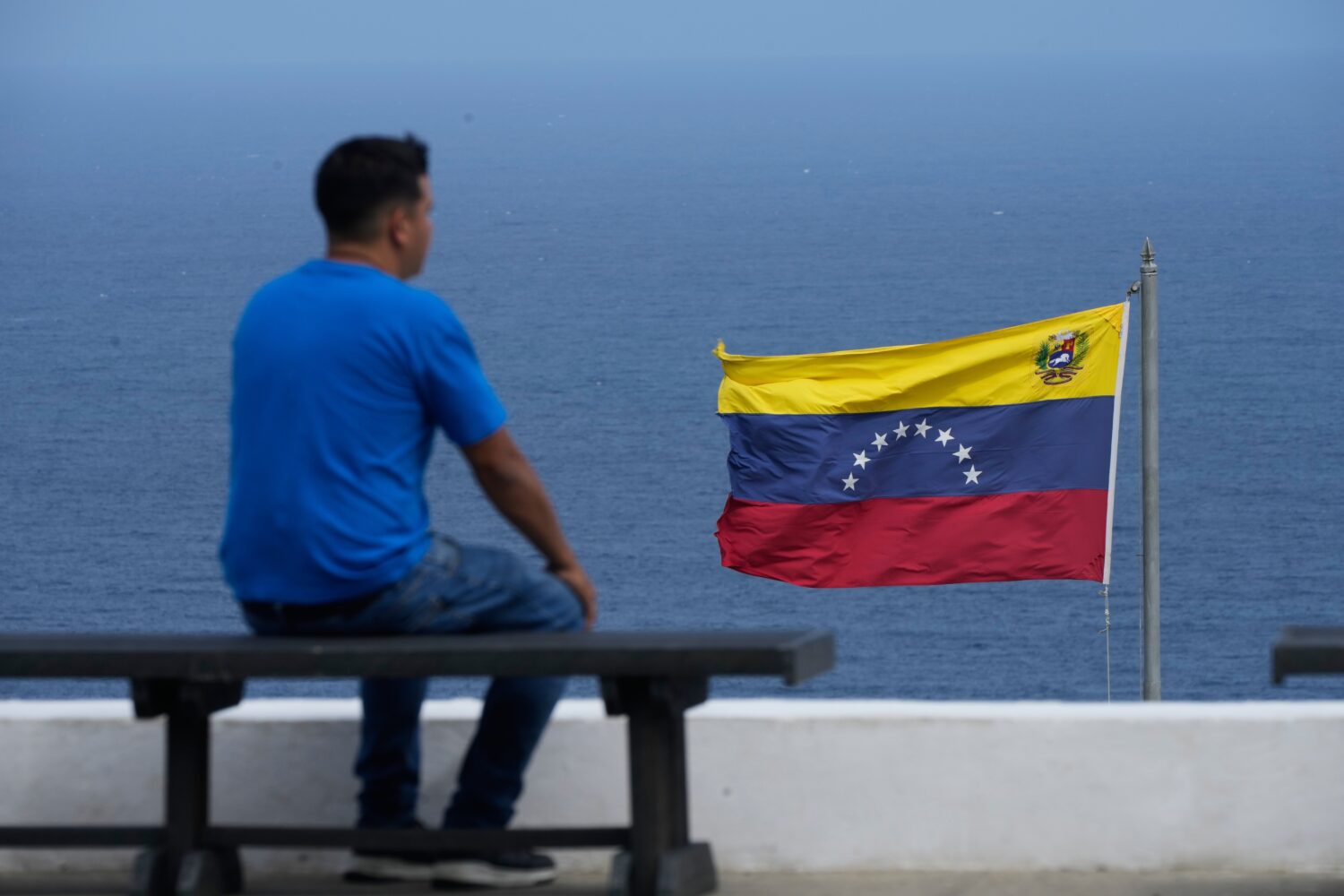 A man looks out at the sea in the city of La Guaira, Venezuela, where the nation's flag flies, Wedn...