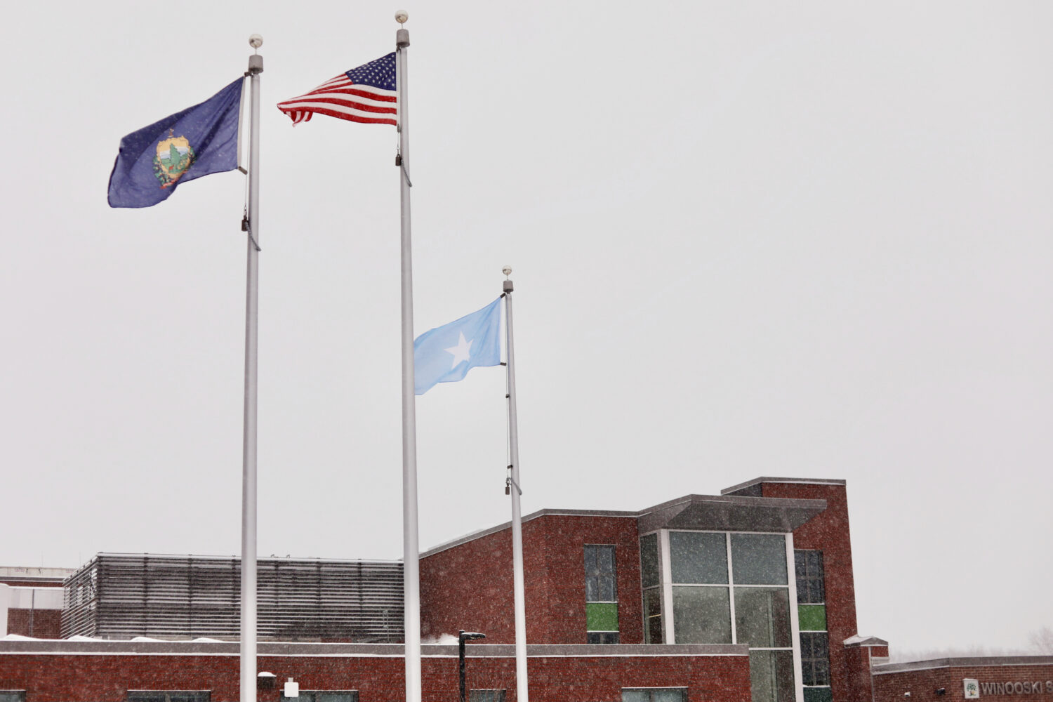 A Somali flag flies alongside the United States and Vermont flags outside the Winooski School Distr...