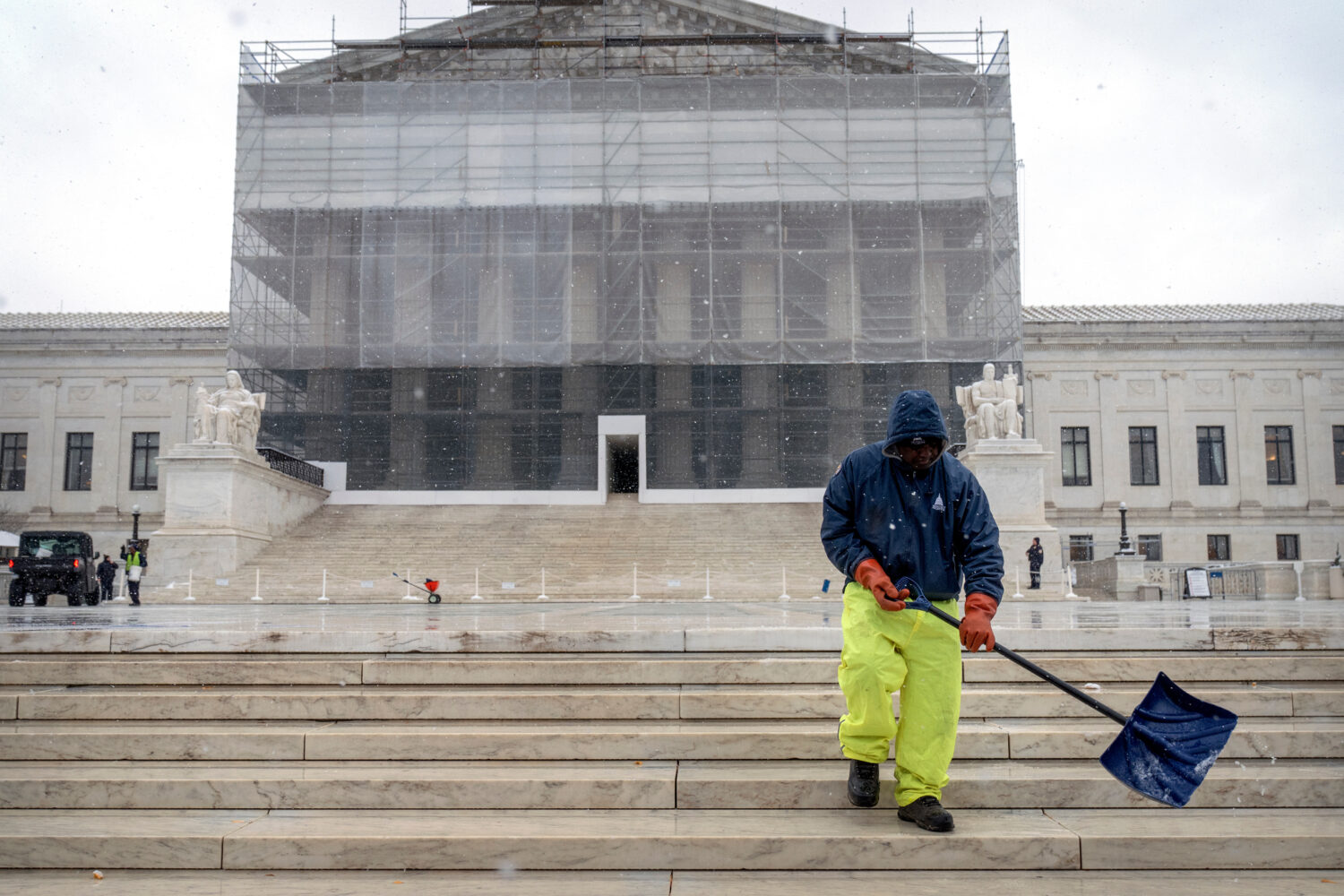 A worker shovels snow and ice in front of the Supreme Court building during the first snowfall of t...