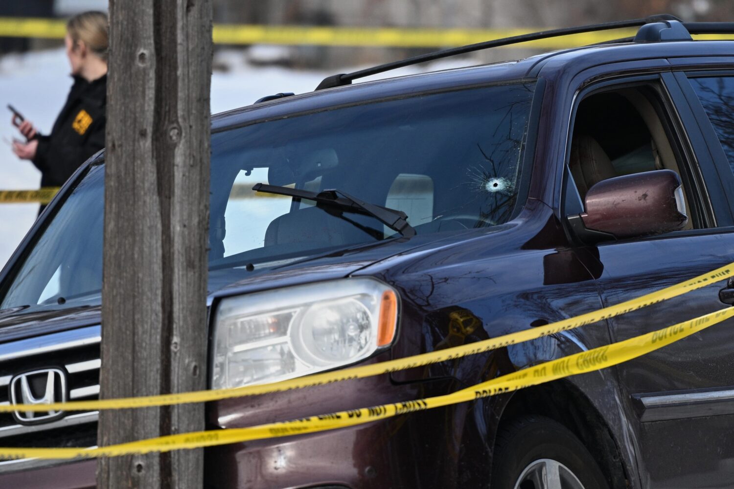 A bullet hole is seen in the windshield as law enforcement officers work at the scene of a shooting...