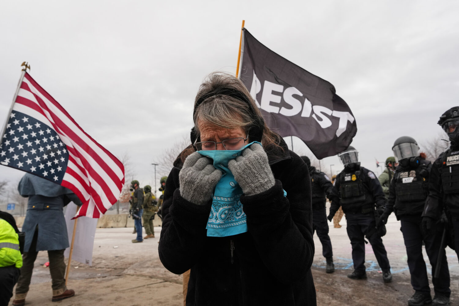 A woman covers her face from tear gas as federal immigration officers confront protesters outside B...