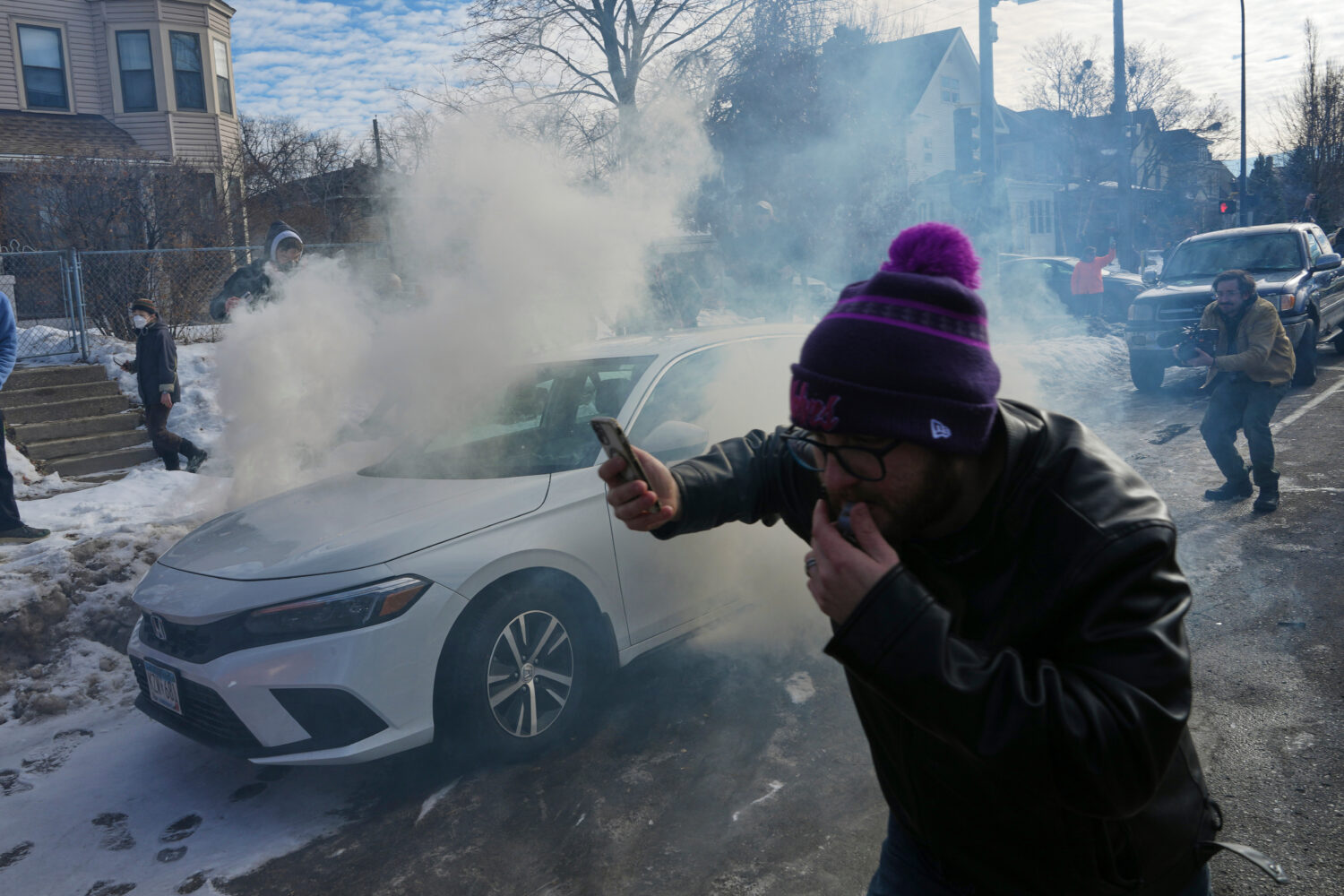 Protesters try to avoid tear gas dispersed by federal agents, Monday, Jan. 12, 2026 in Minneapolis ...
