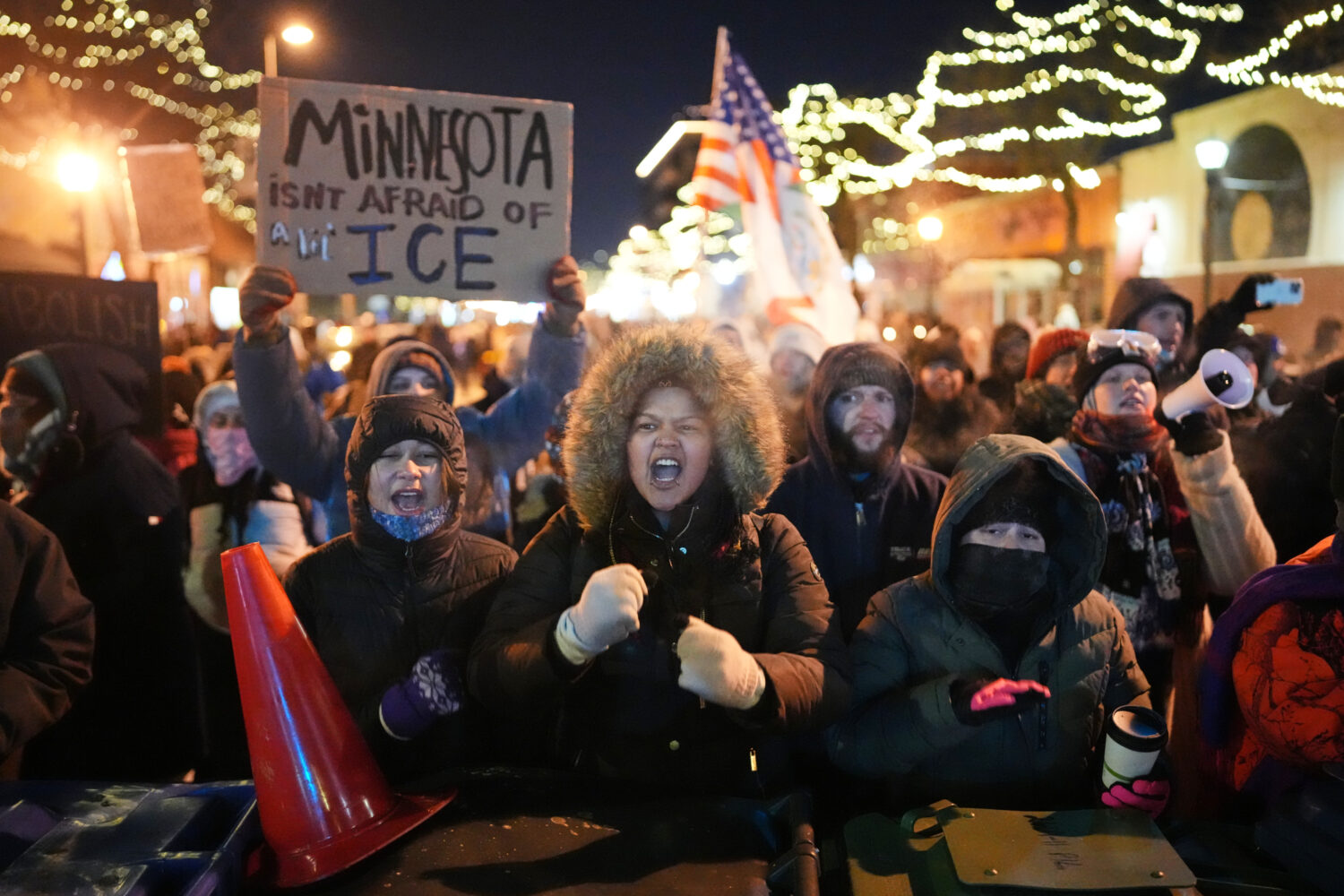 Protesters chant and bang on trash cans as they stand behind a makeshift barricade during a protest...