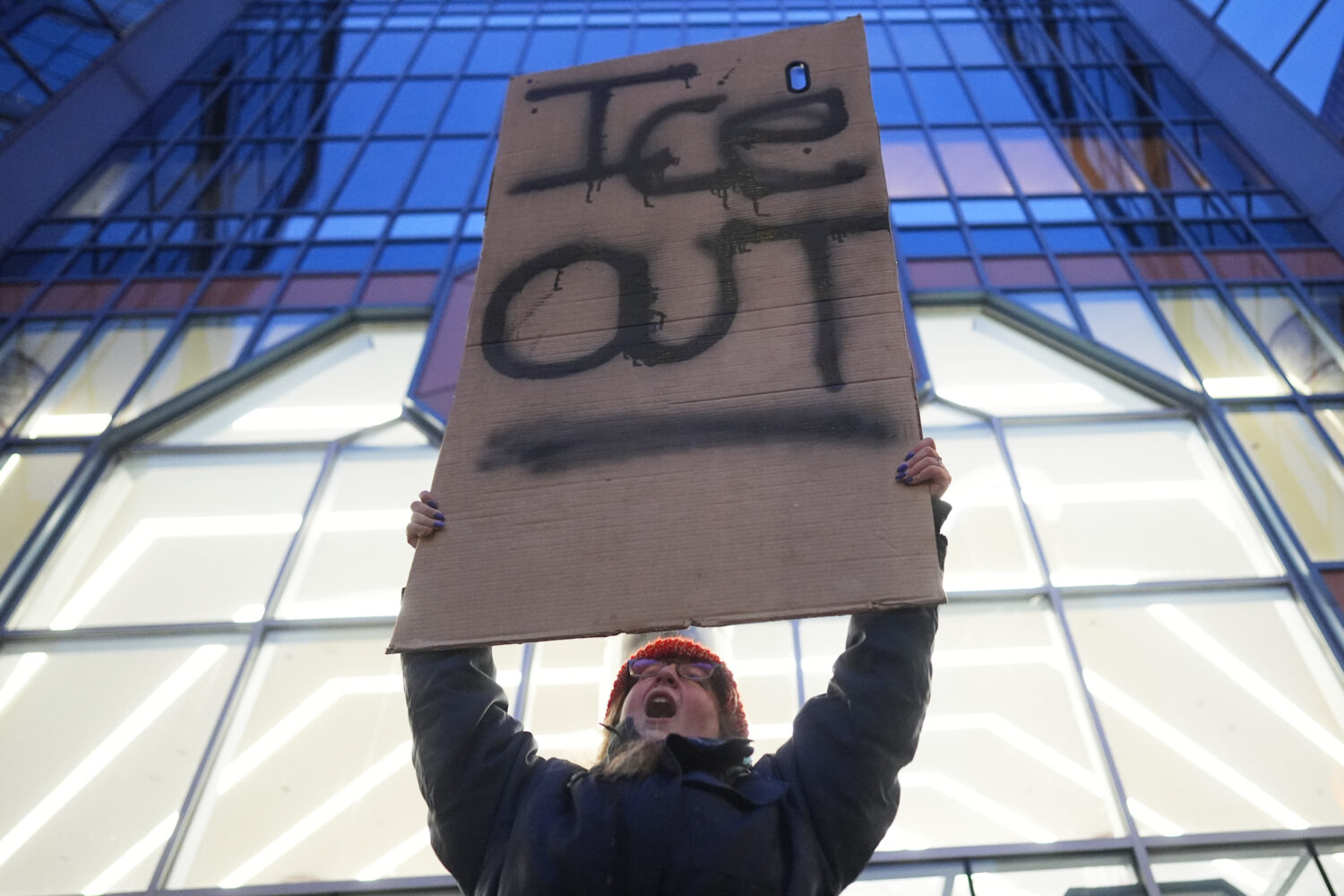 A demonstrator holds a sign reading "ICE OUT" during a protest outside the office of Sen. Amy Klobu...