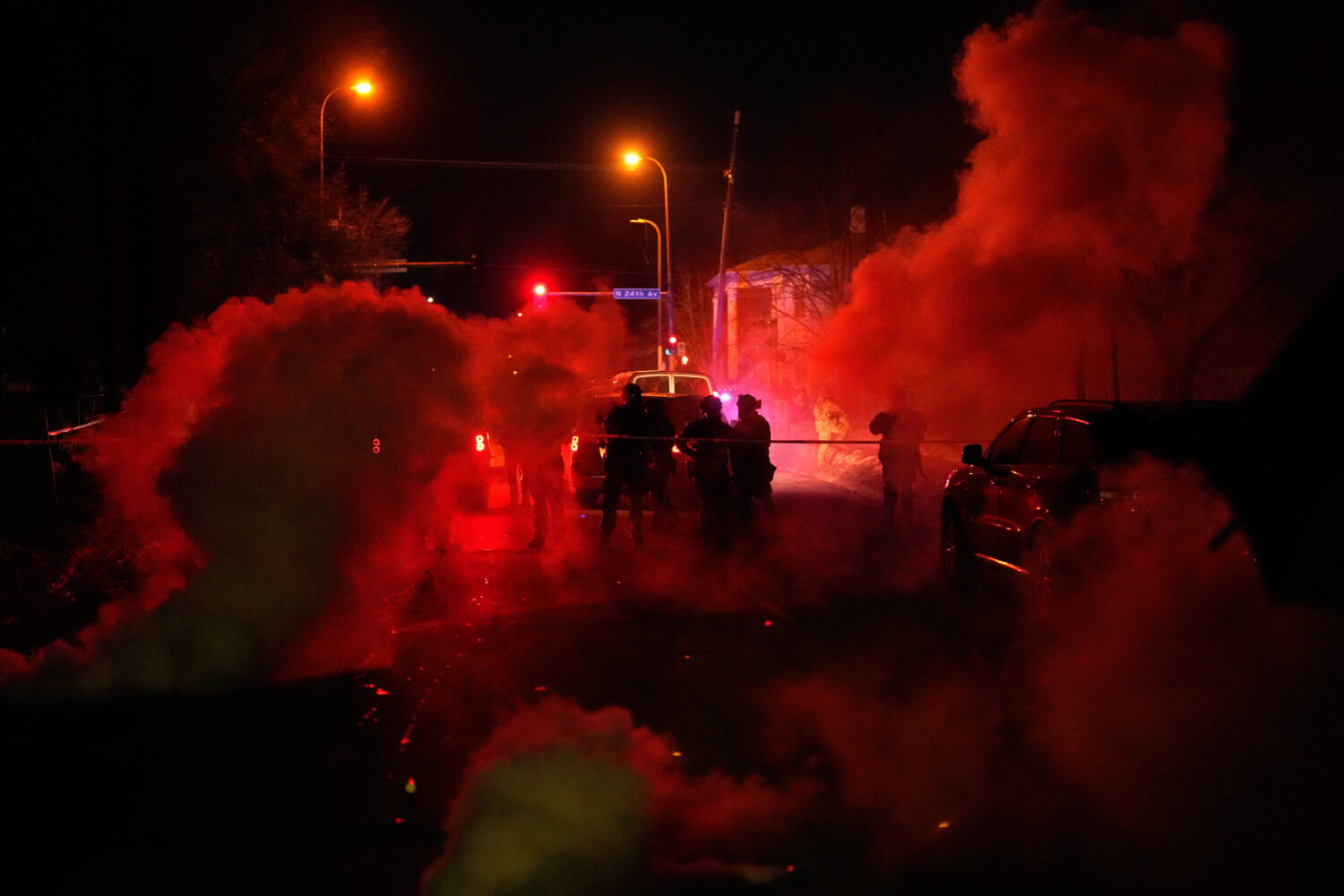 Tear gas surrounds federal law enforcement officers as they leave a scene after a shooting on Wedne...