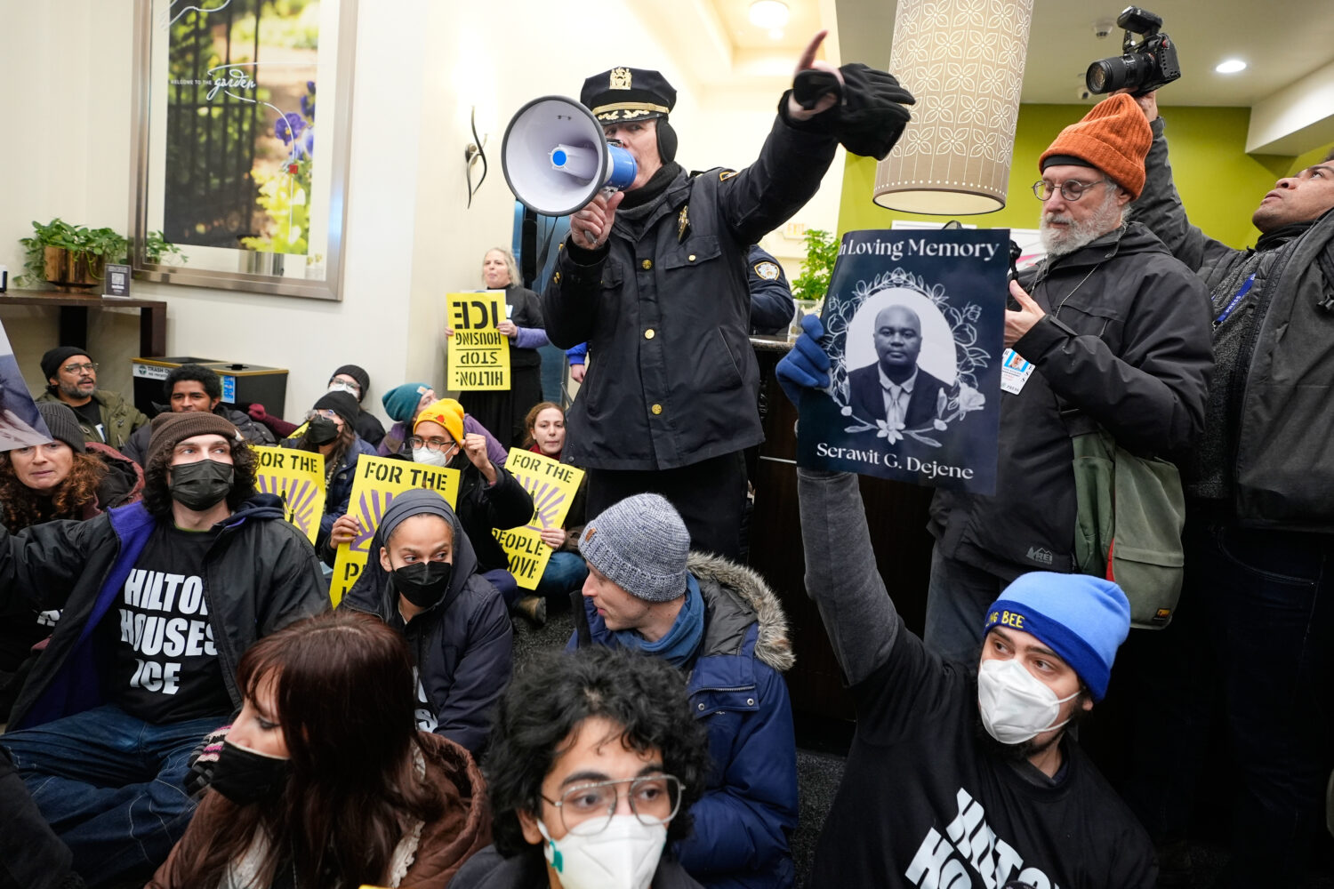 A police officer, top, makes an announcement about impending arrests during a sit-in in the lobby o...