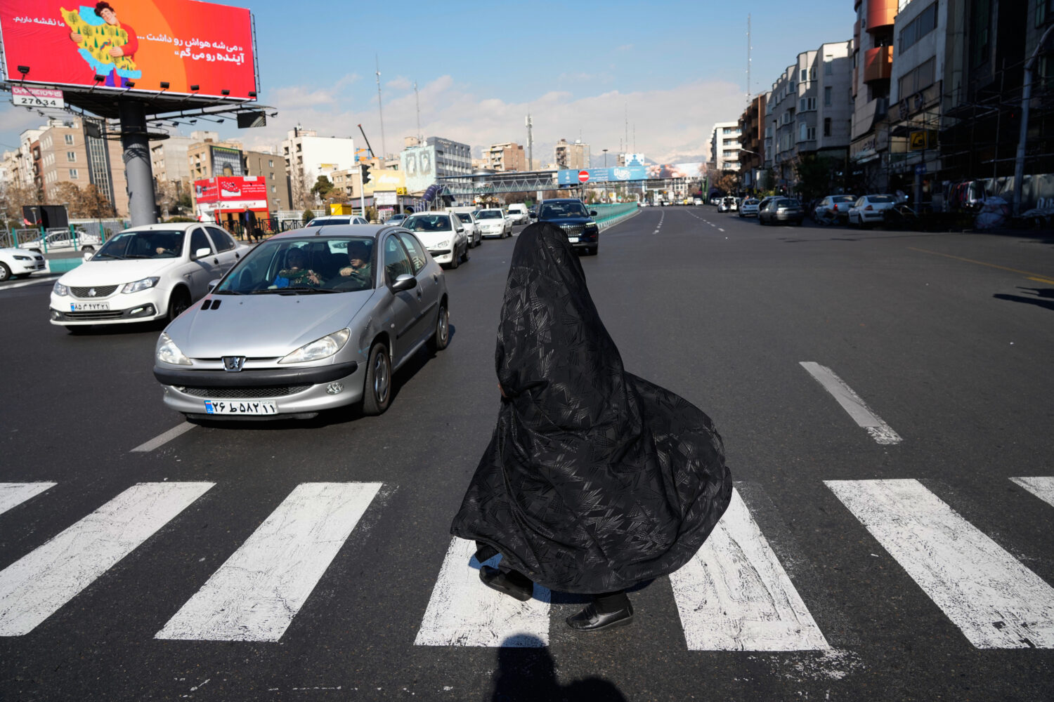 A woman crosses an intersection in downtown Tehran, Iran, Friday, Jan. 16, 2026. (AP Photo/Vahid Sa...