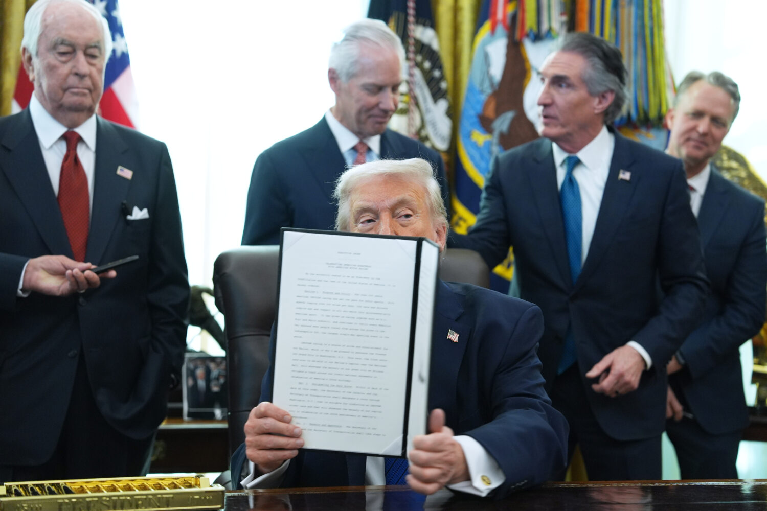President Donald Trump holds an executive order he signed in the Oval Office of the White House, Fr...
