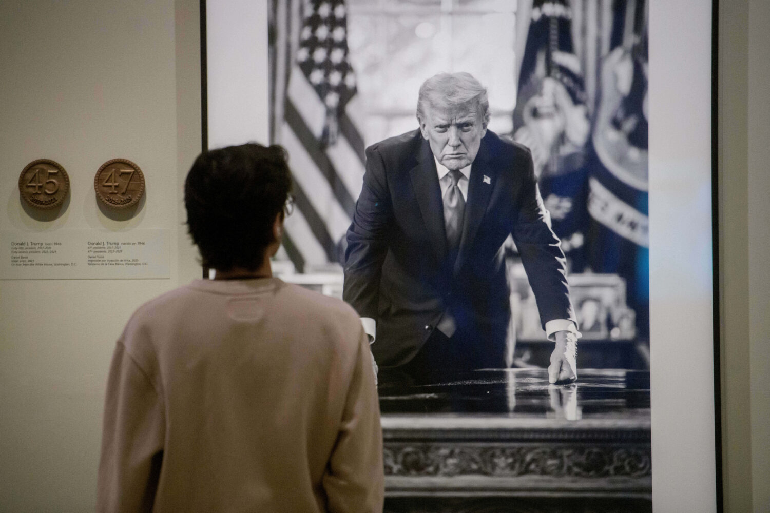 A visitor stops to look at a photograph of President Donald Trump and a short plaque next to it are...