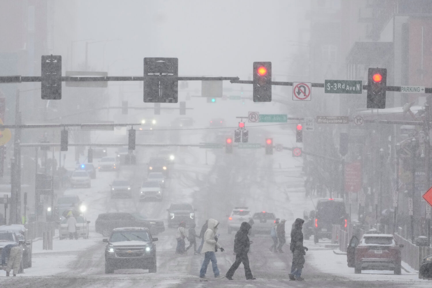 Pedestrians cross the street along Broadway during a winter storm Saturday, Jan. 24, 2026, in Nashv...