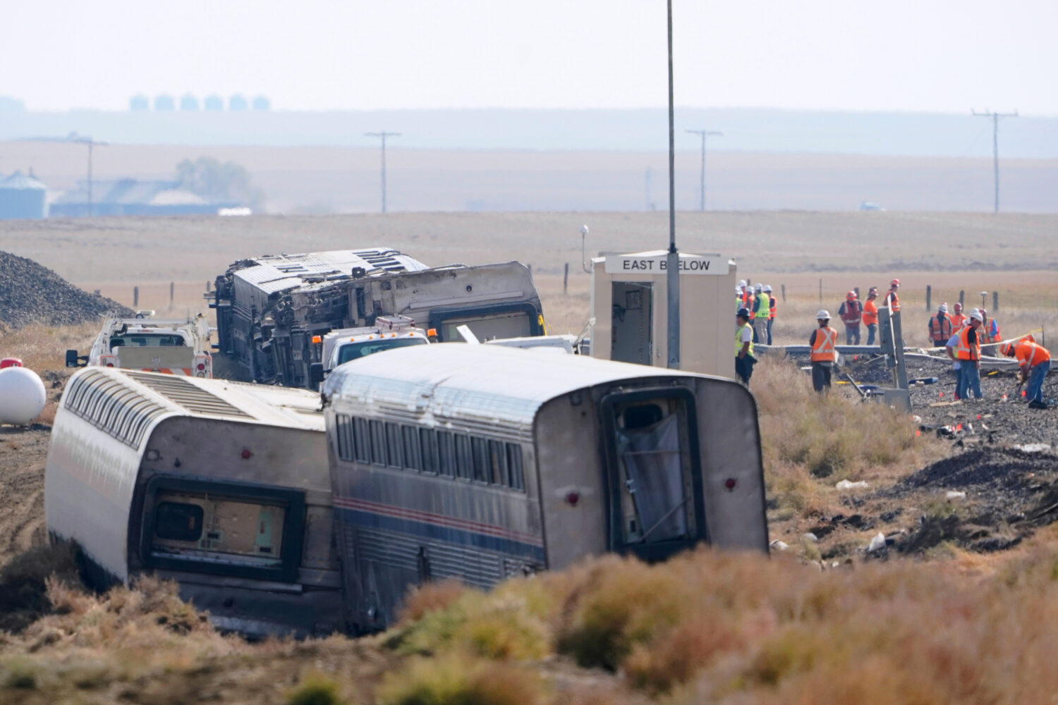 FILE - In this Sept. 27, 2021, file photo, workers stand near train tracks next to overturned cars ...