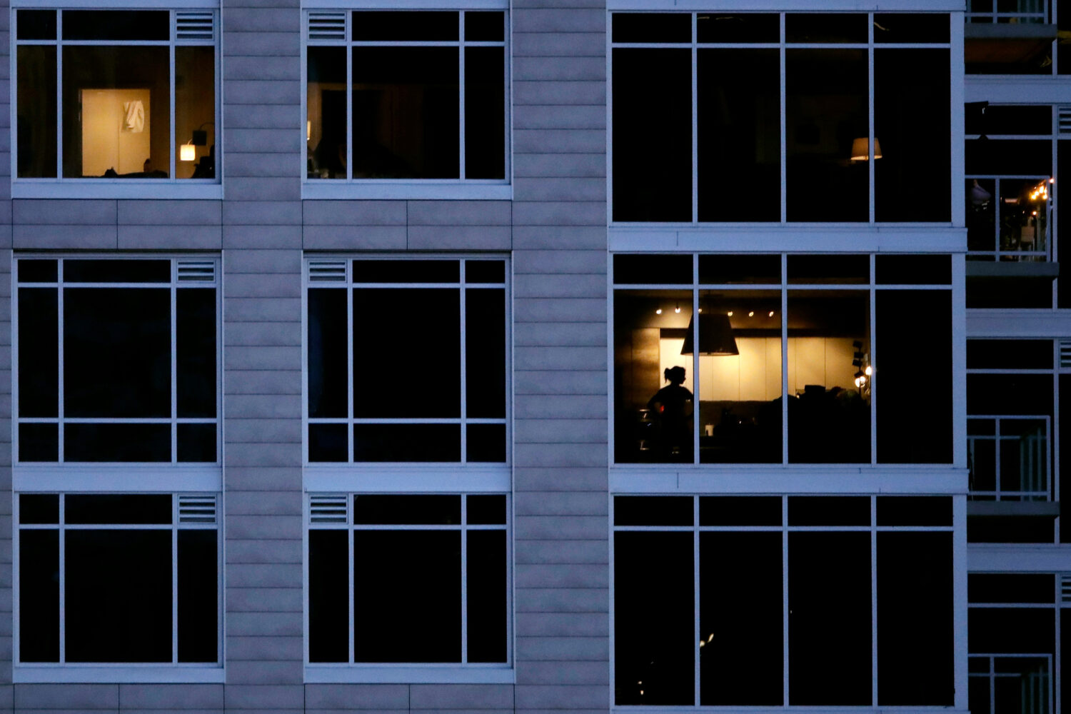 FILE - A person looks out of a window in an apartment building in Kansas City, Mo., May 3, 2020. (A...