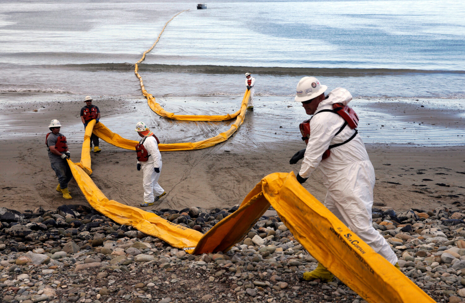 FILE - Workers prepare an oil containment boom at Refugio State Beach, north of Goleta, Calif., on ...