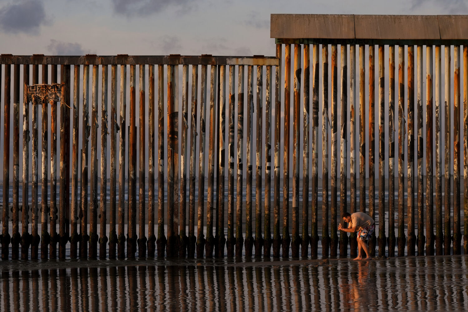 FILE - A man takes an image with his phone next to where the border wall separating Mexico and the ...