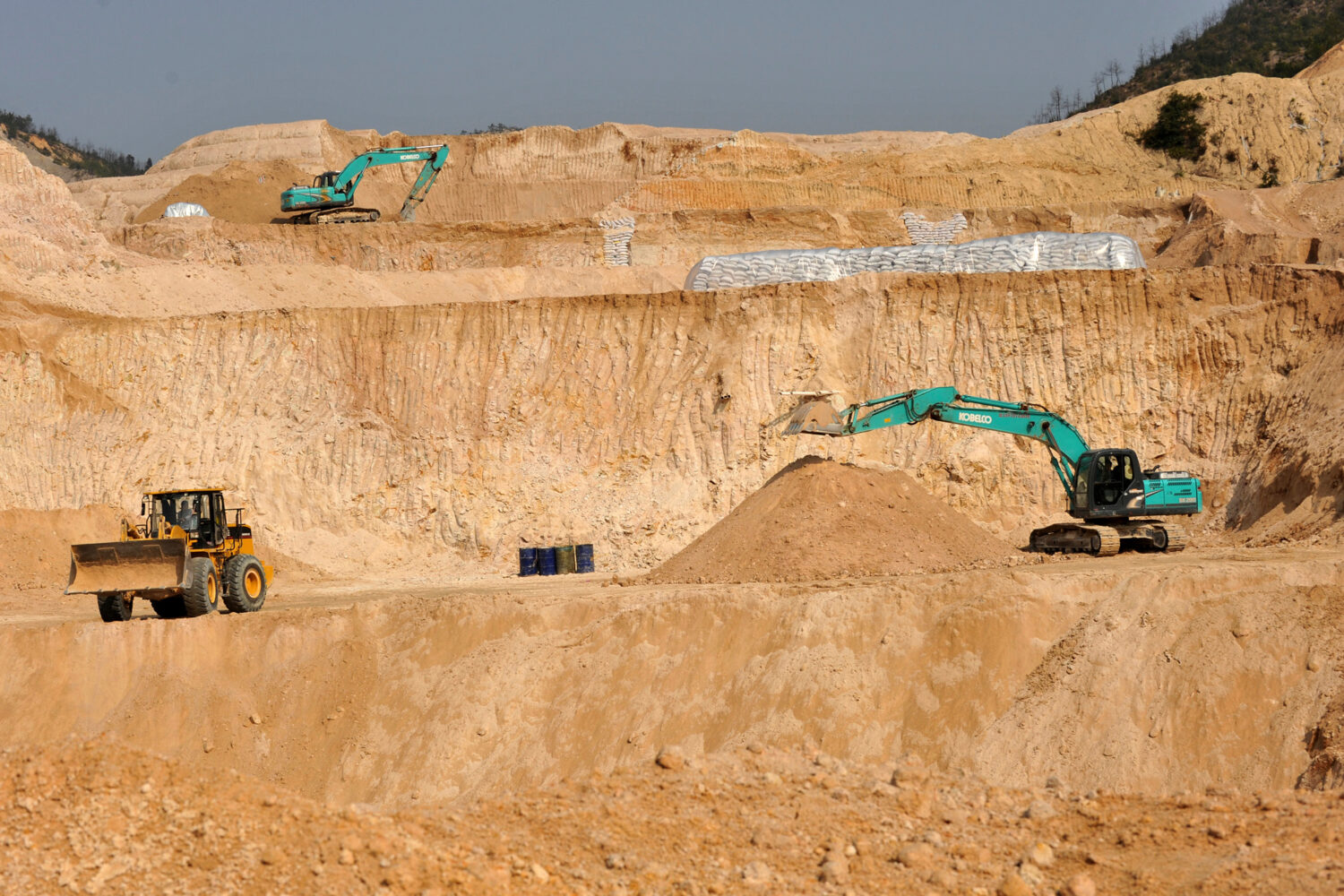 FILE - Workers use machinery to dig at a rare earth mine in Ganxian county in central China's Jiang...