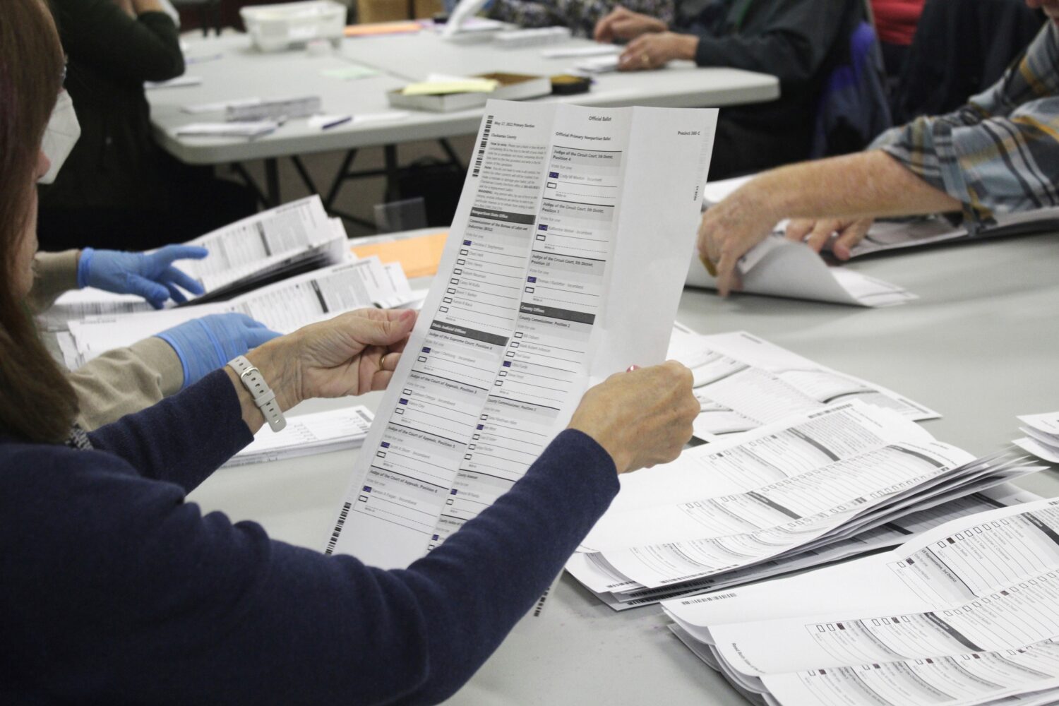 FILE - An election worker examines a ballot at the Clackamas County Elections office May 19, 2022, ...