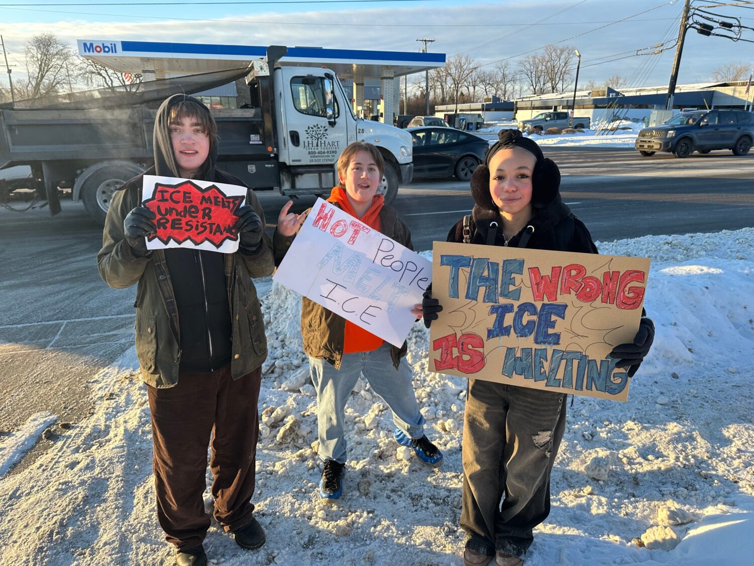 From left, Asher O'Donnel, Ryan Maddox and Amari Perez-Wayner hold signs as several dozen Groves Hi...