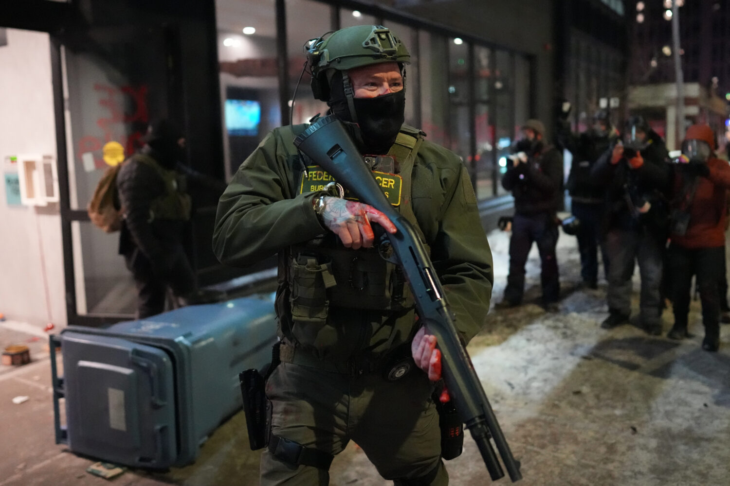 A federal agent stands guard near a hotel during a noise demonstration protest in response to feder...