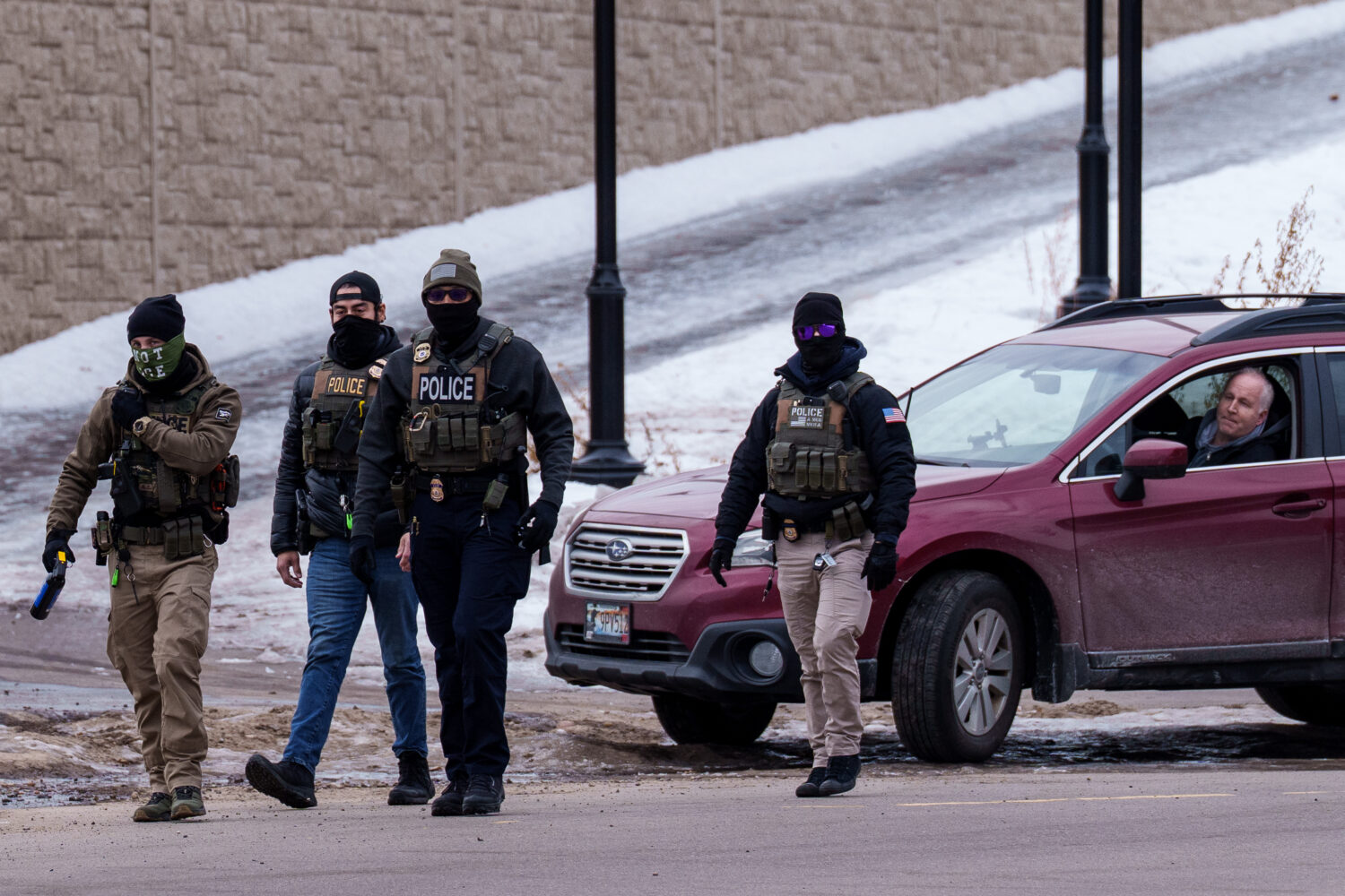 A person looks out of their vehicle as Immigration and Customs Enforcement (ICE) agents walk away, ...