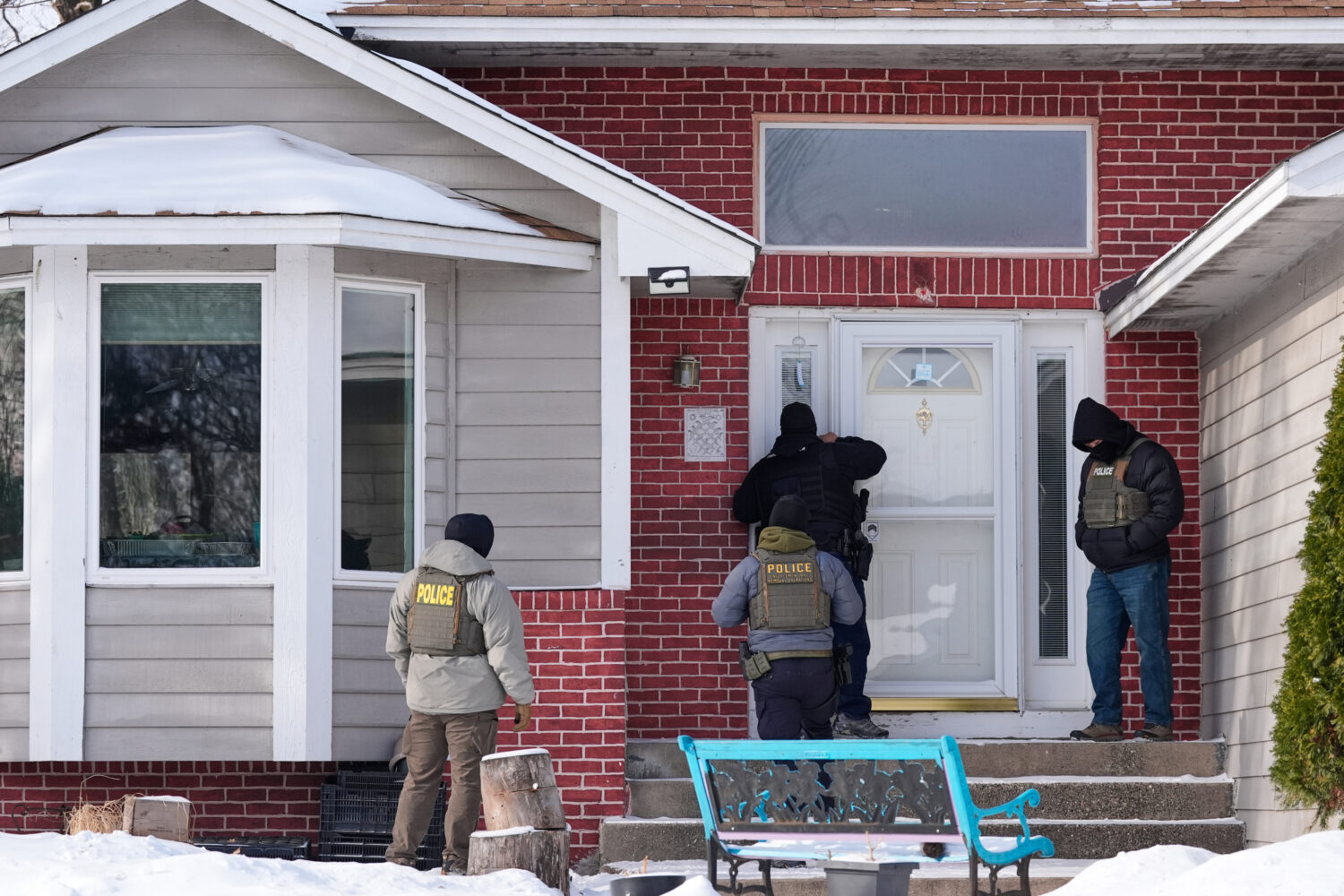 Federal immigration officers look through the window of a home Tuesday, Jan. 20, 2026, in Maplewood...